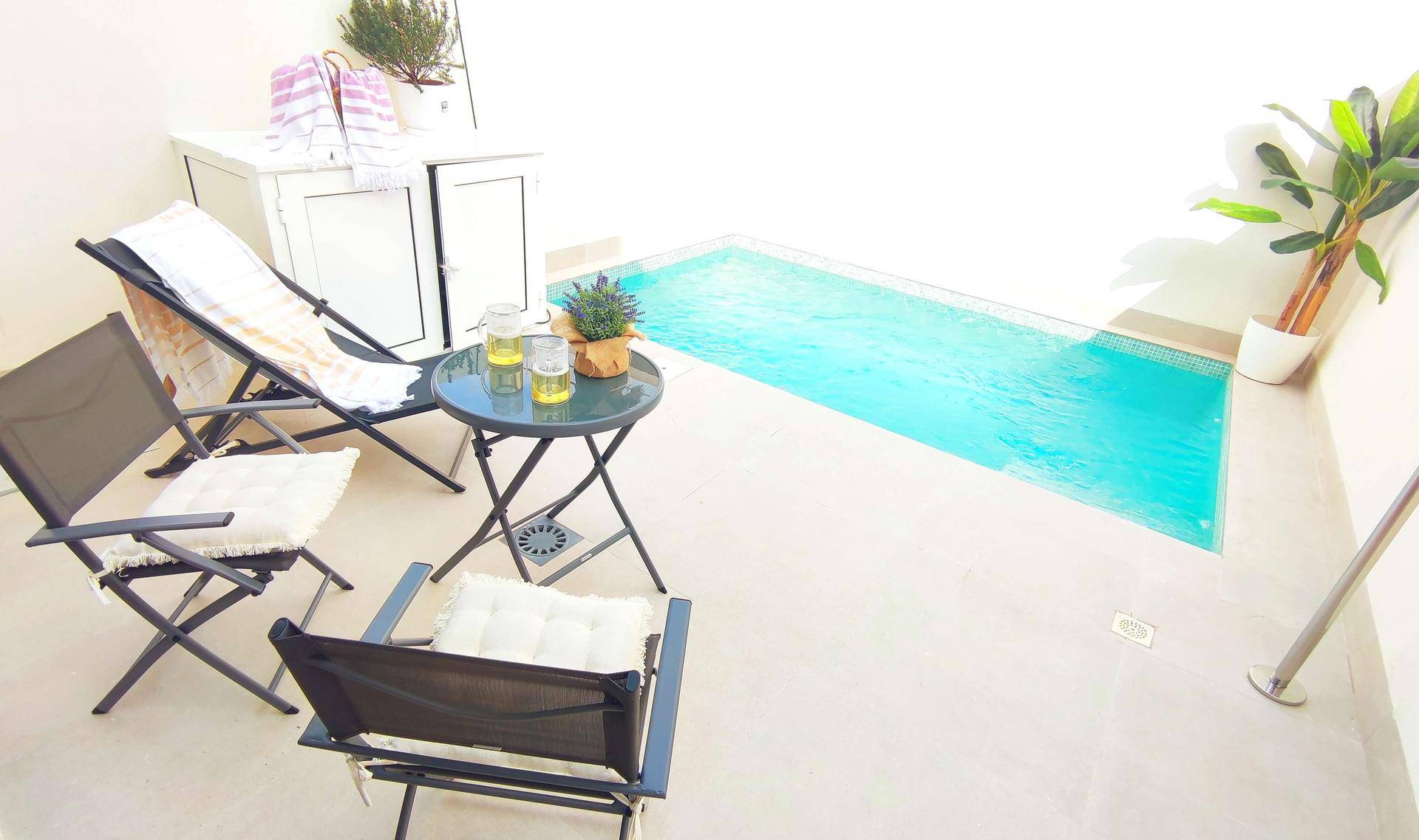 Sonniger Patio mit kleinem Pool, Liegestühlen und einem Tisch für entspannte Stunden im Freien.