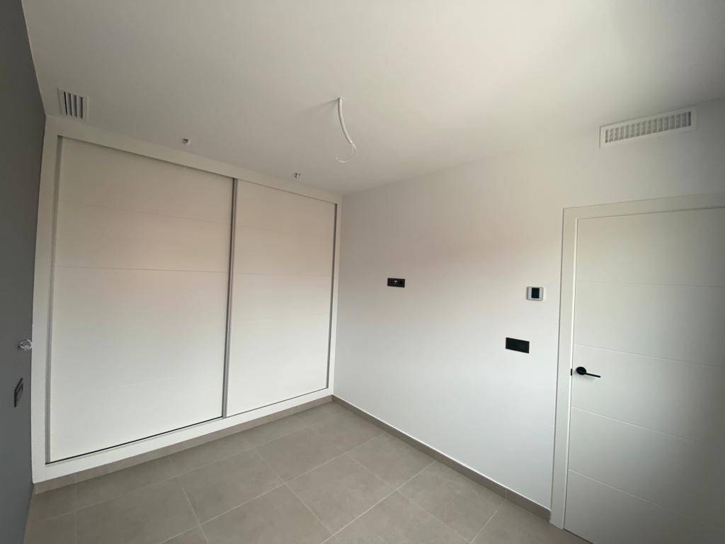 Helles Schlafzimmer mit Einbauschrank und modernen Fliesenboden.