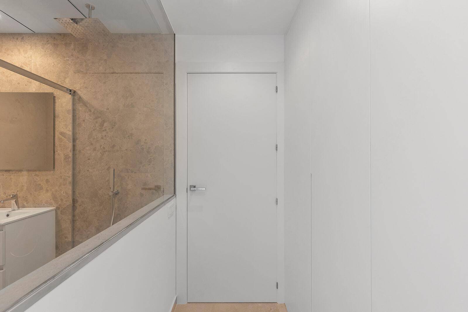 Heller Flur mit Zugang zu einem modernen Badezimmer, das eine begehbare Dusche zeigt.