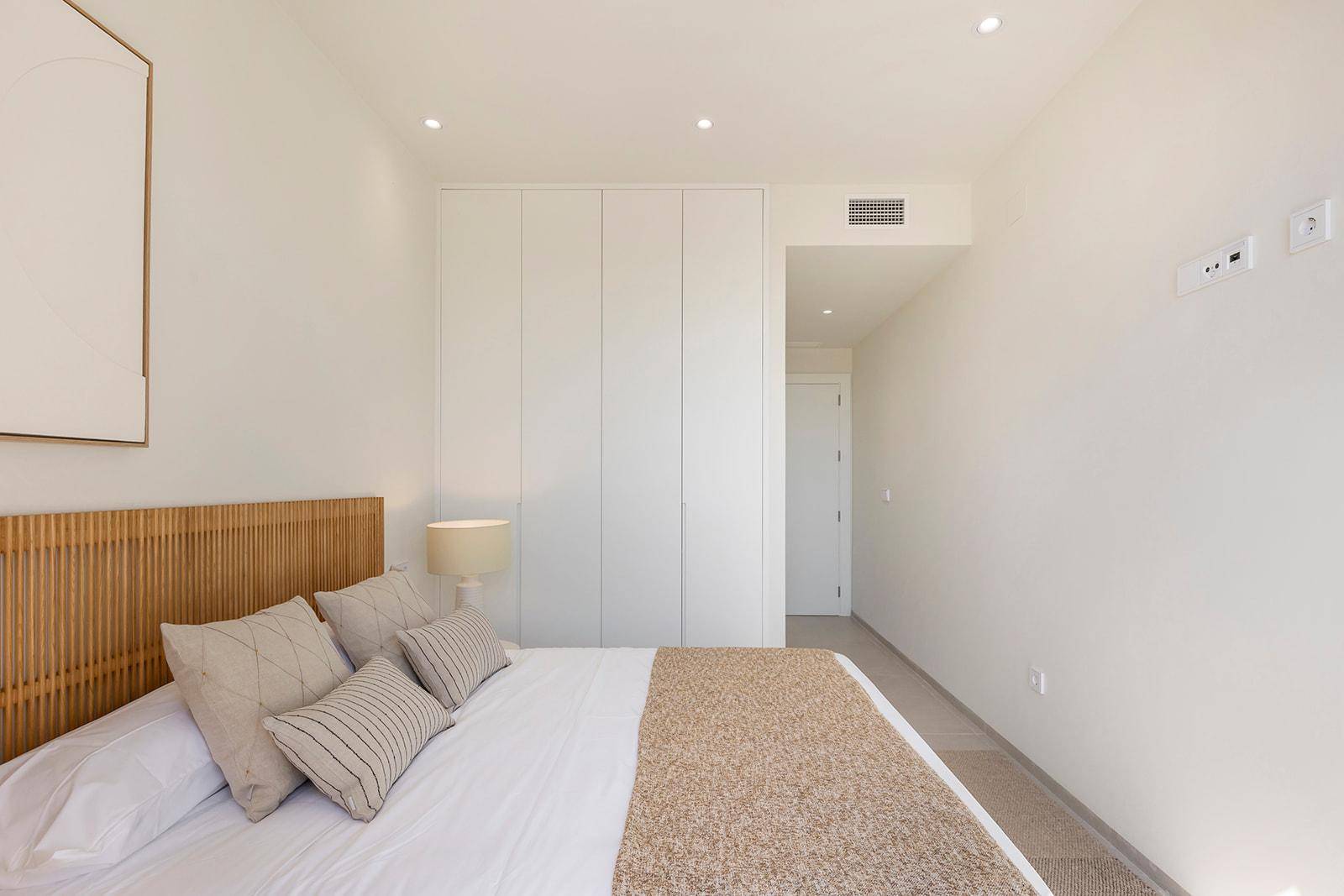 Modernes Schlafzimmer mit Einbauschränken, indirekter Beleuchtung und schlichter Einrichtung.
