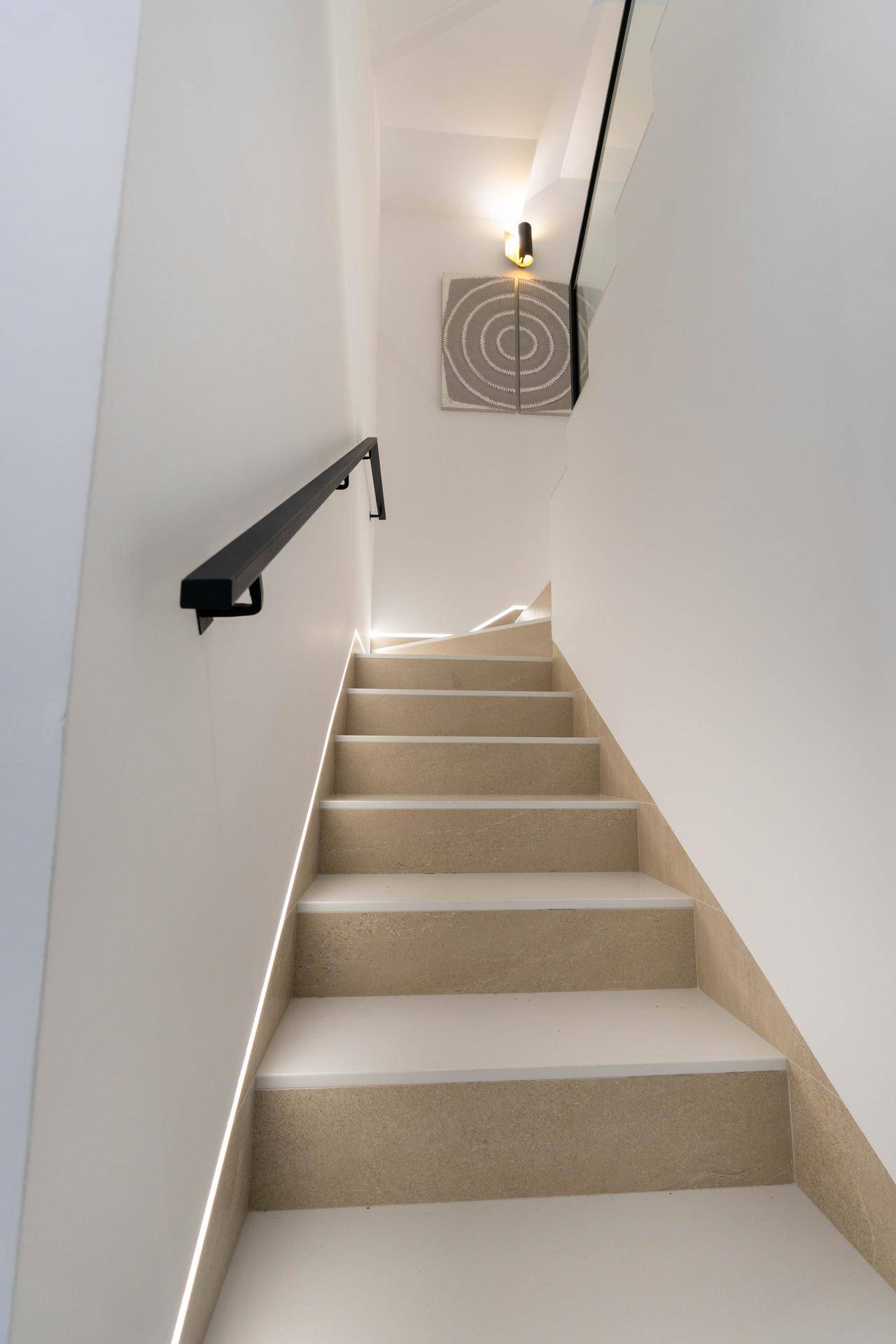 Moderne Treppe mit indirekter Beleuchtung und elegantem Geländer, führt in die oberen Etagen.