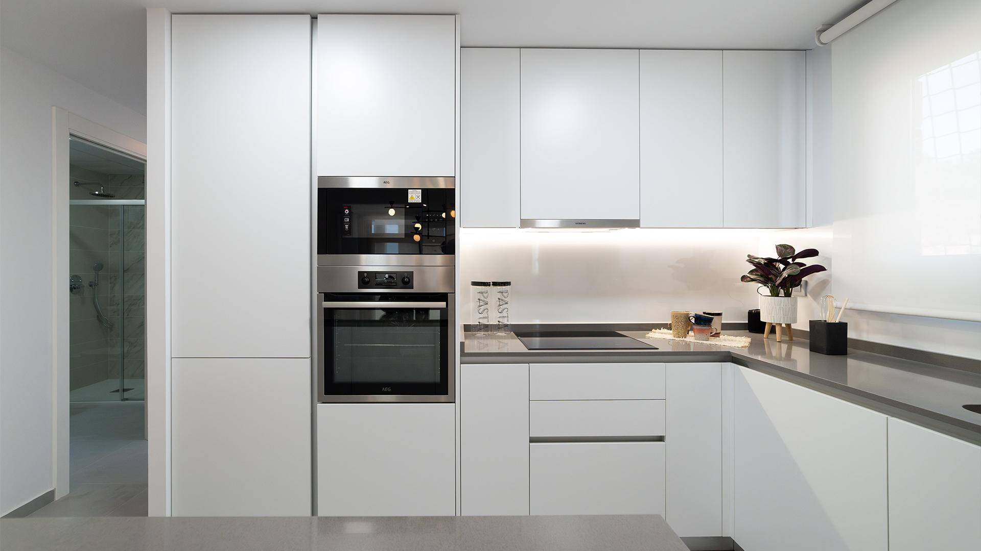 Moderne weiße Einbauküche mit integrierten Geräten und minimalistischem Design.