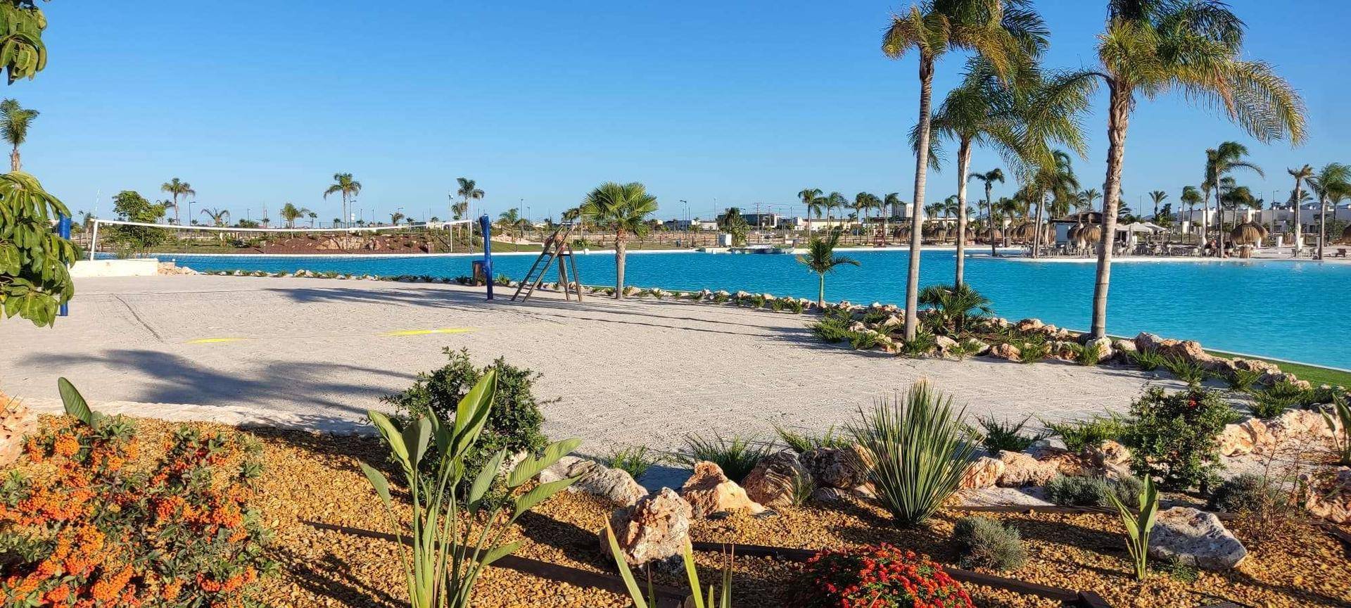 Weitläufige Freizeitanlage mit großem Pool, Sandstrand und Beachvolleyballfeld.