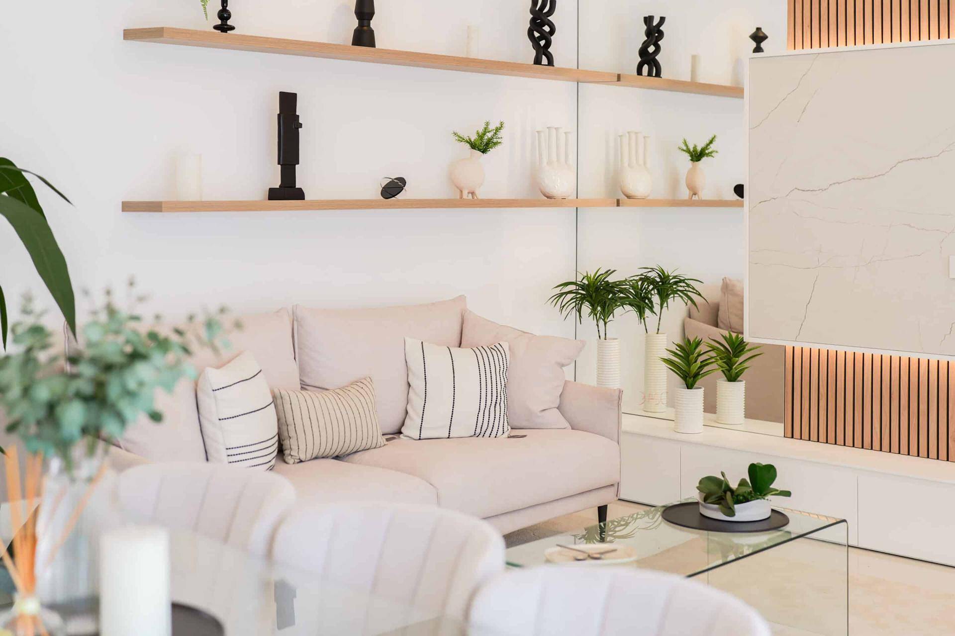 Gemütlicher Wohnbereich mit hellem Sofa, Holzakzenten und dekorativen Pflanzen.