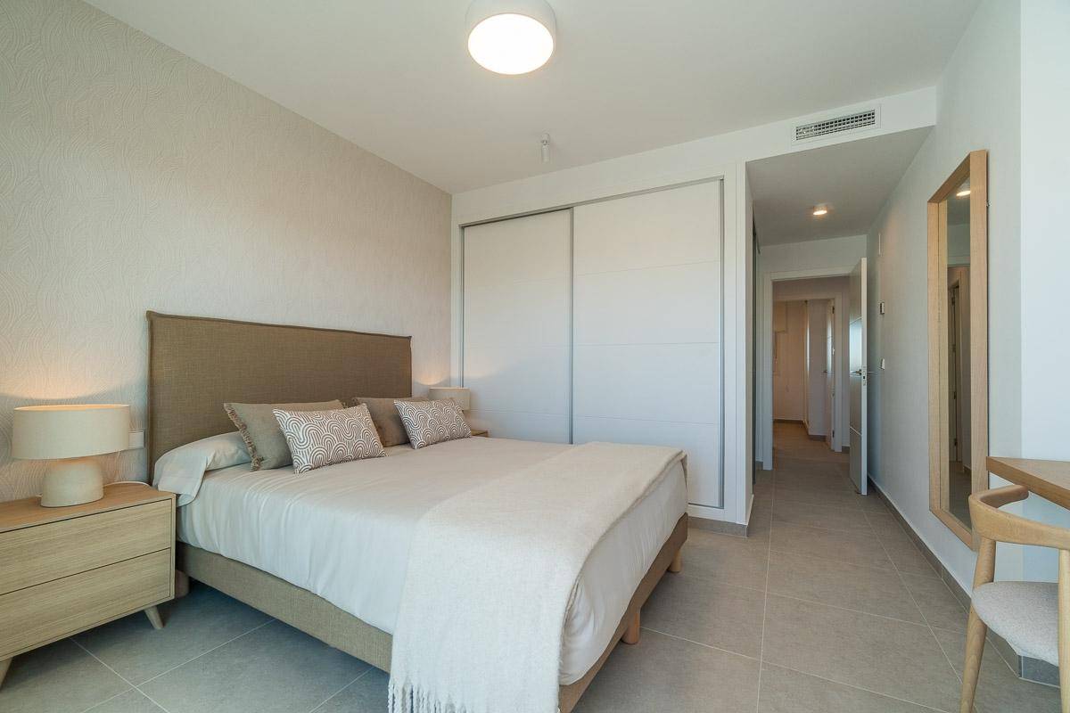 Geräumiges Schlafzimmer mit Doppelbett, Einbauschrank und einem kleinen Schreibtischbereich.
