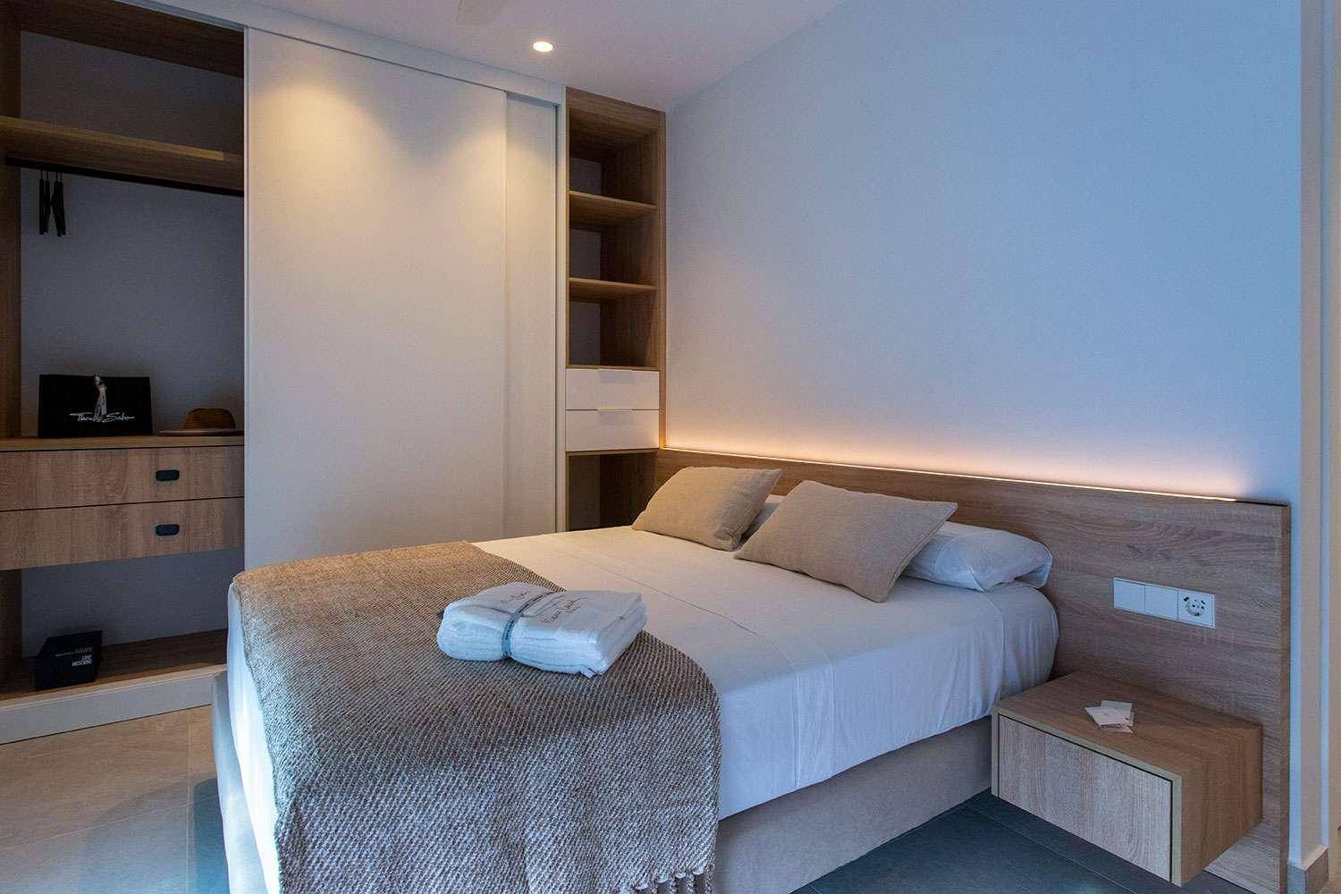 Modernes Schlafzimmer mit Einbauschränken, Holzdetails und indirekter Beleuchtung für eine angenehme Atmosphäre.