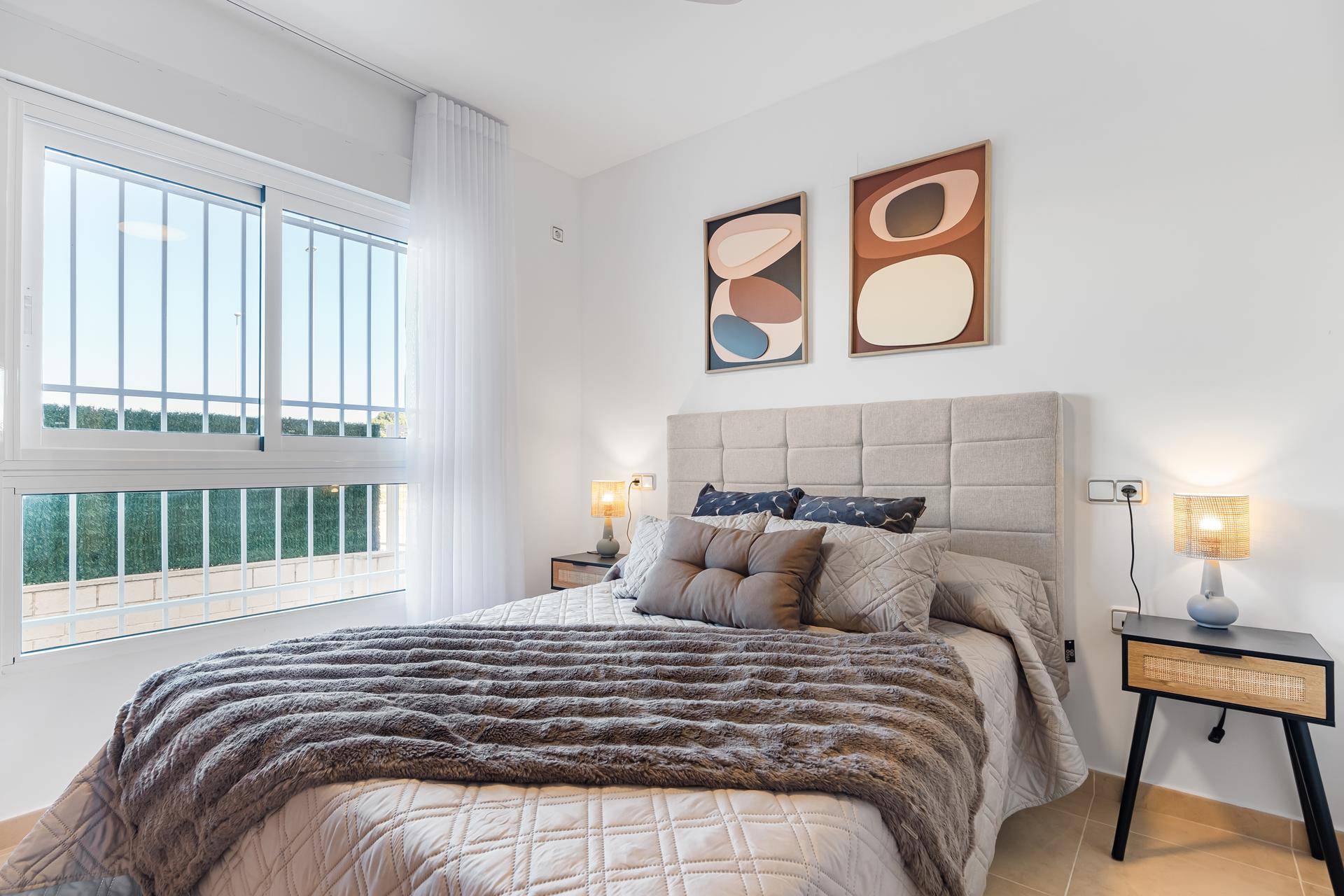 Helles Schlafzimmer mit Doppelbett, Nachttischen und Fenster mit Blick ins Grüne.