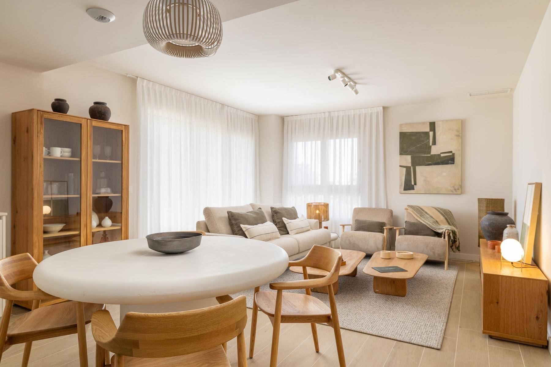 Offener Wohn- und Essbereich mit modernem Esstisch, bequemen Sofas und großen Fenstern.