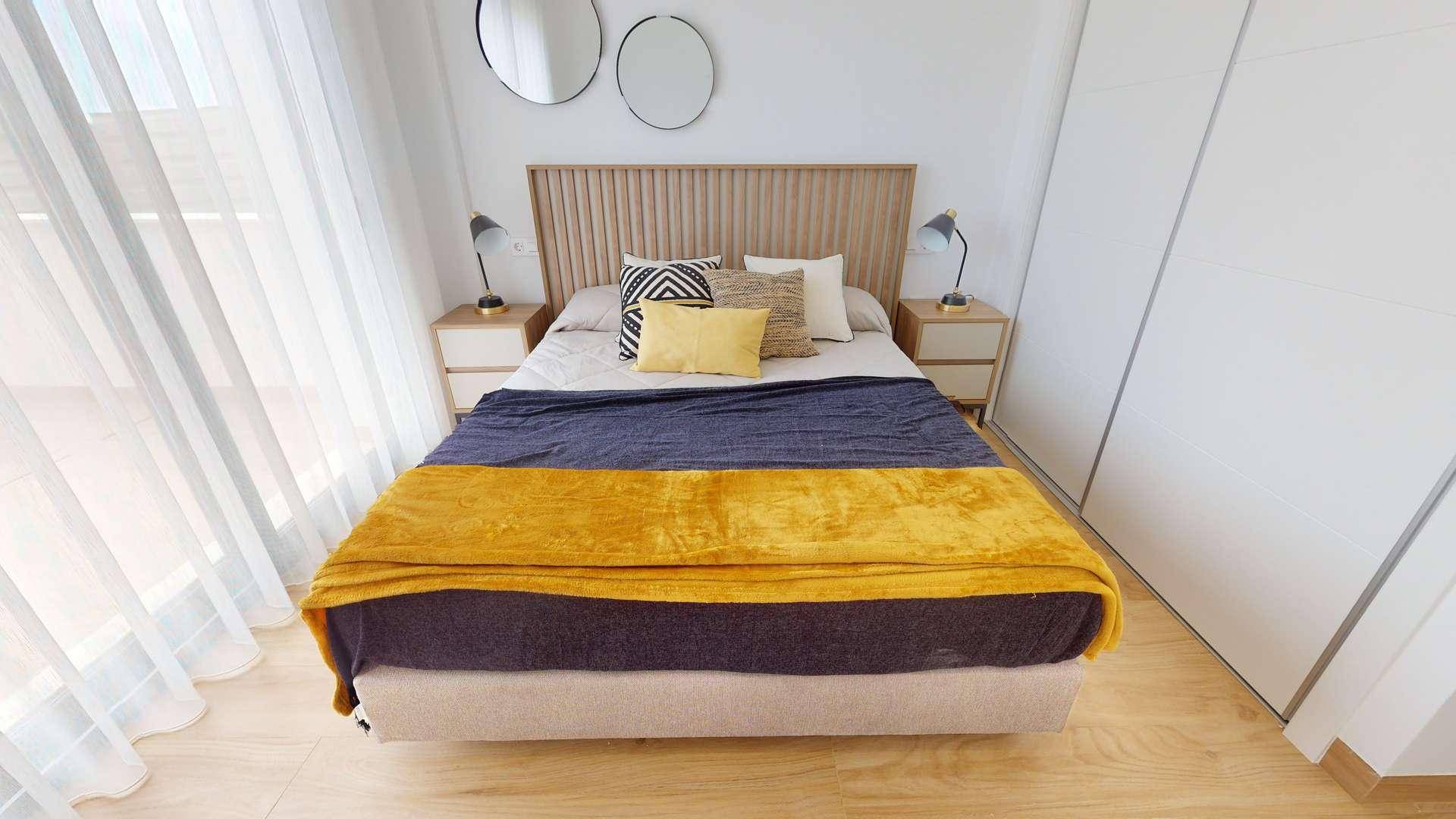 Helles Schlafzimmer mit Doppelbett, Nachttischen und integriertem Kleiderschrank.