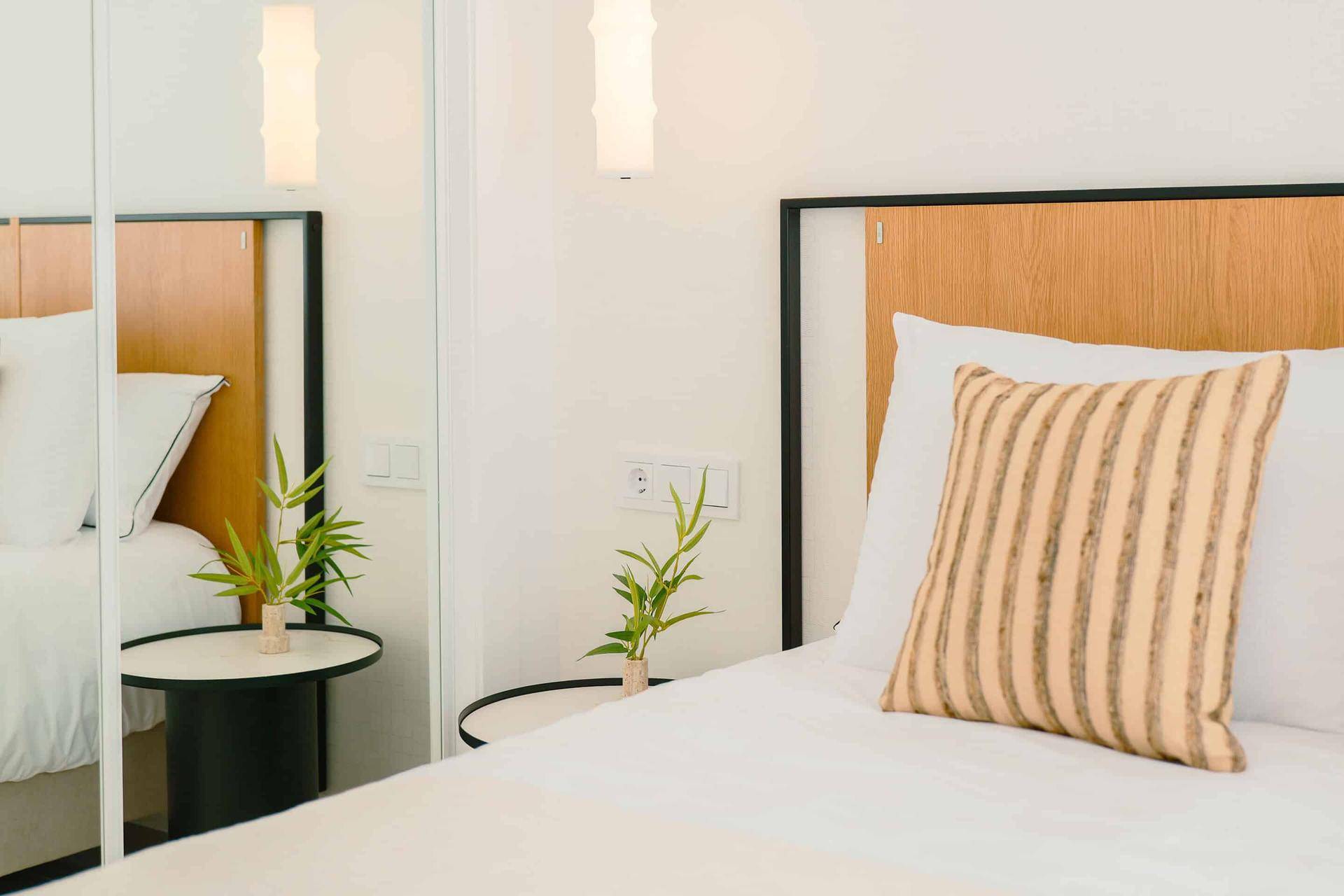 Helles Schlafzimmer mit Holzkopfteil, Nachttisch und Spiegel, modern und einladend gestaltet.