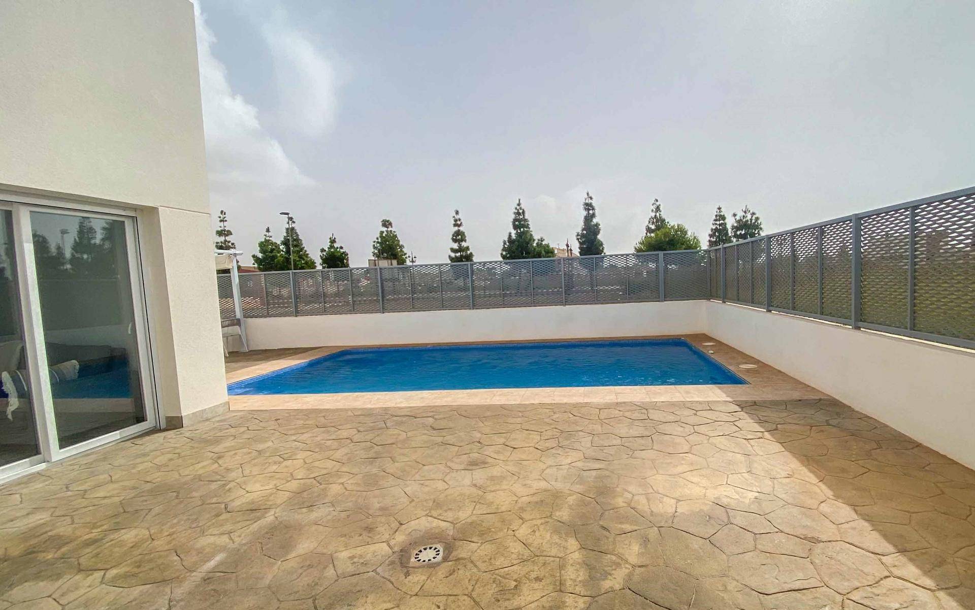 Großer Poolbereich mit gepflasterter Fläche und Blick auf die Umgebung.