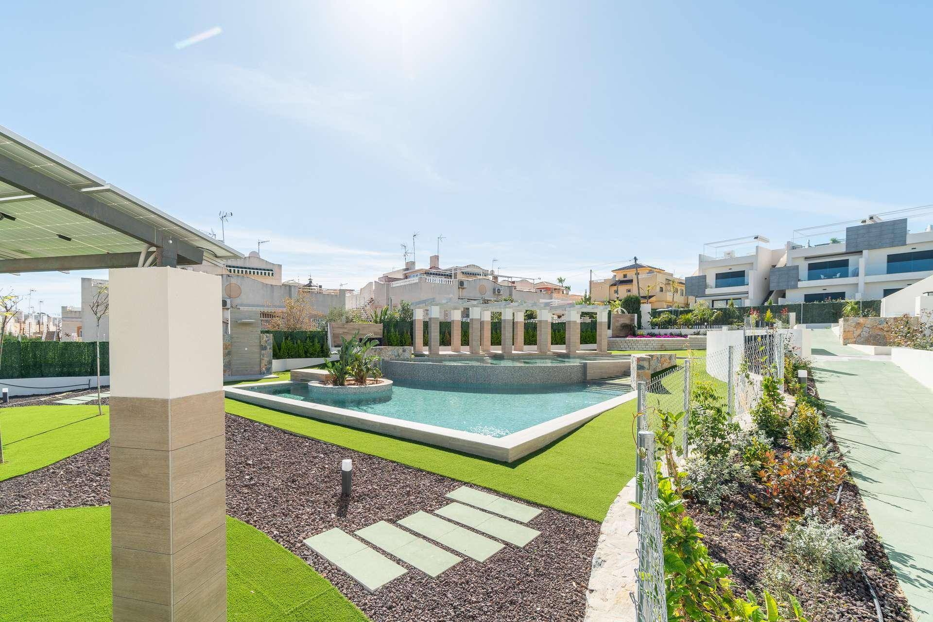 Attraktiver Poolbereich mit Säulenarchitektur, Kunstrasen und Photovoltaikanlage im Hintergrund.