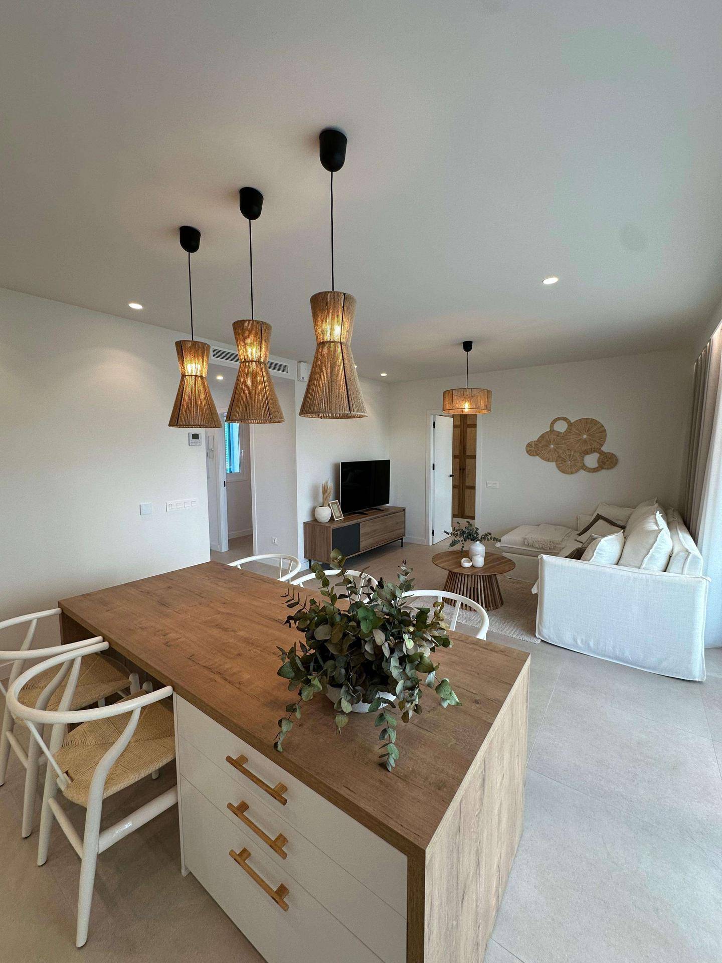 Moderner Essbereich mit Holztisch und Hängeleuchten, offen zum Wohnzimmer und Küche.