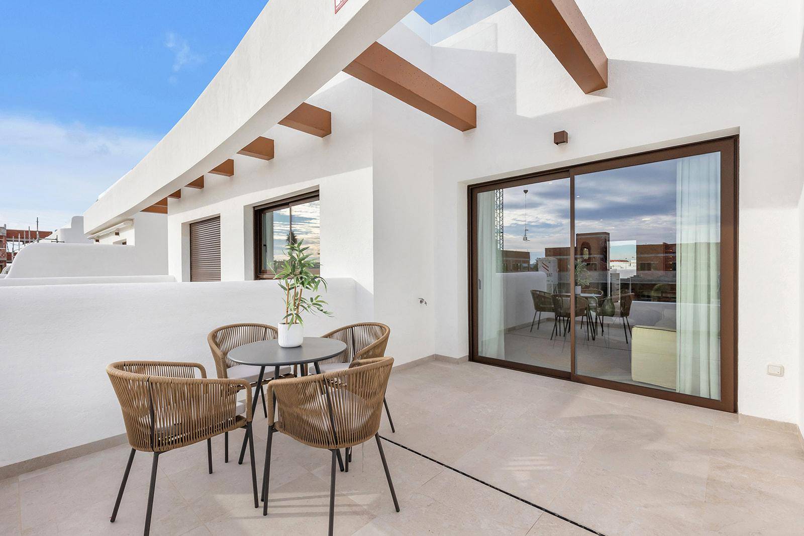 Heller Balkon mit Sitzgruppe und Zugang durch eine große Glasschiebetür.