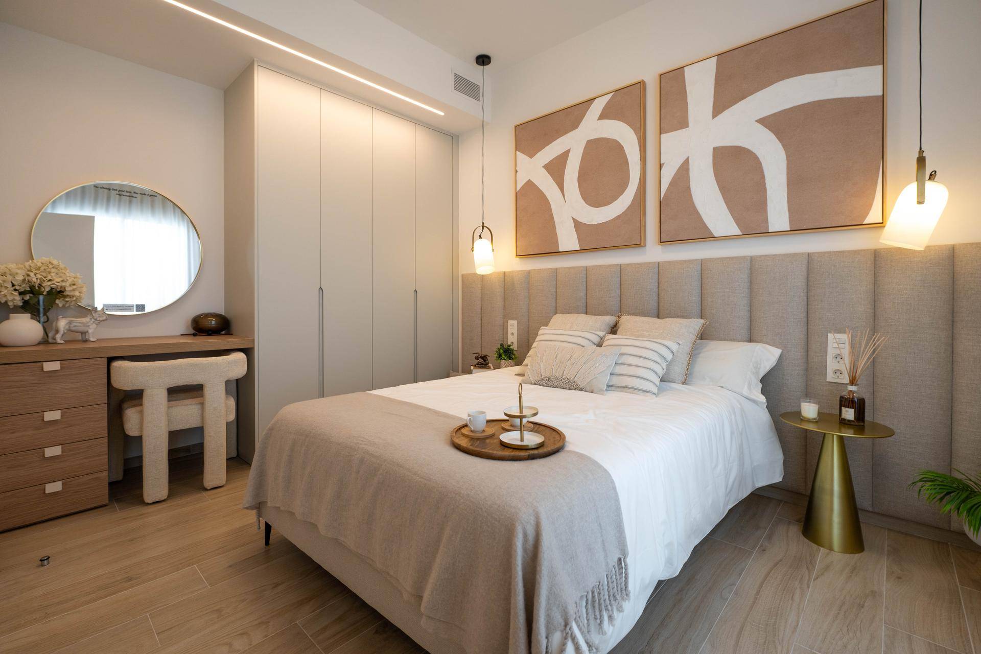 Helles Schlafzimmer mit beigem Kopfteil, Einbauschränken und stilvoller Dekoration.
