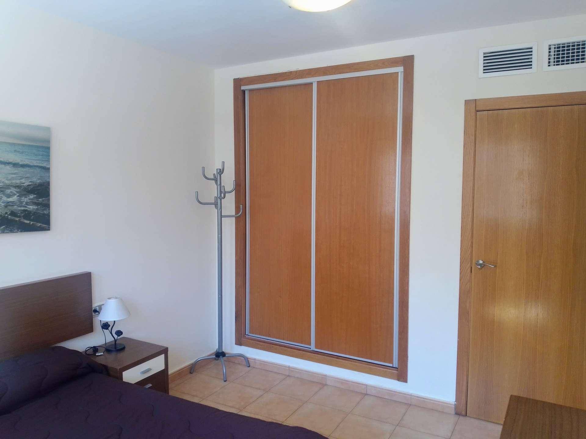 Schlafzimmer mit integriertem Kleiderschrank und Fliesenboden, bietet praktischen Stauraum.