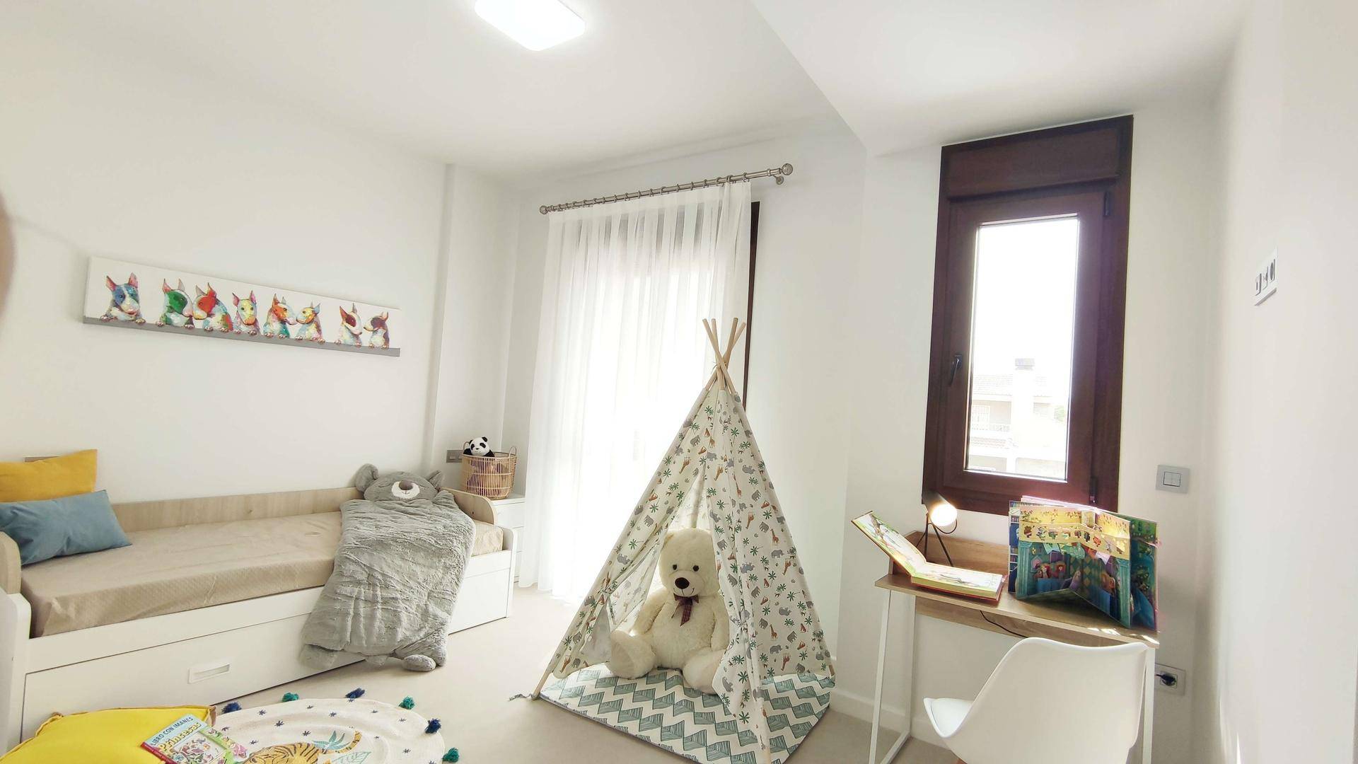 Freundliches Kinderzimmer mit Bett, Spielzelt und Schreibtisch am Fenster.