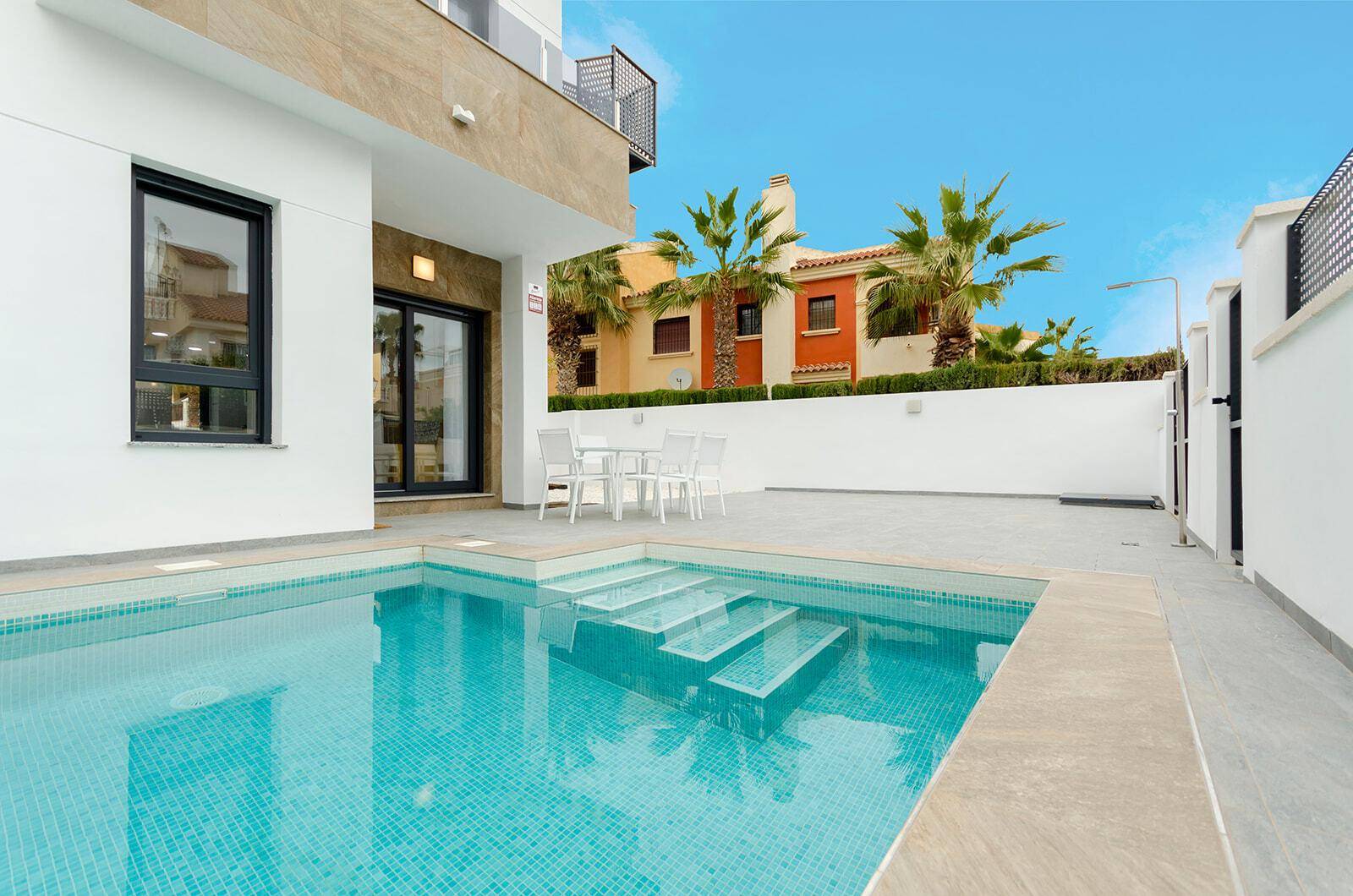 Sonniger Außenbereich mit privatem Pool und weißer Sitzgruppe für entspannte Stunden.