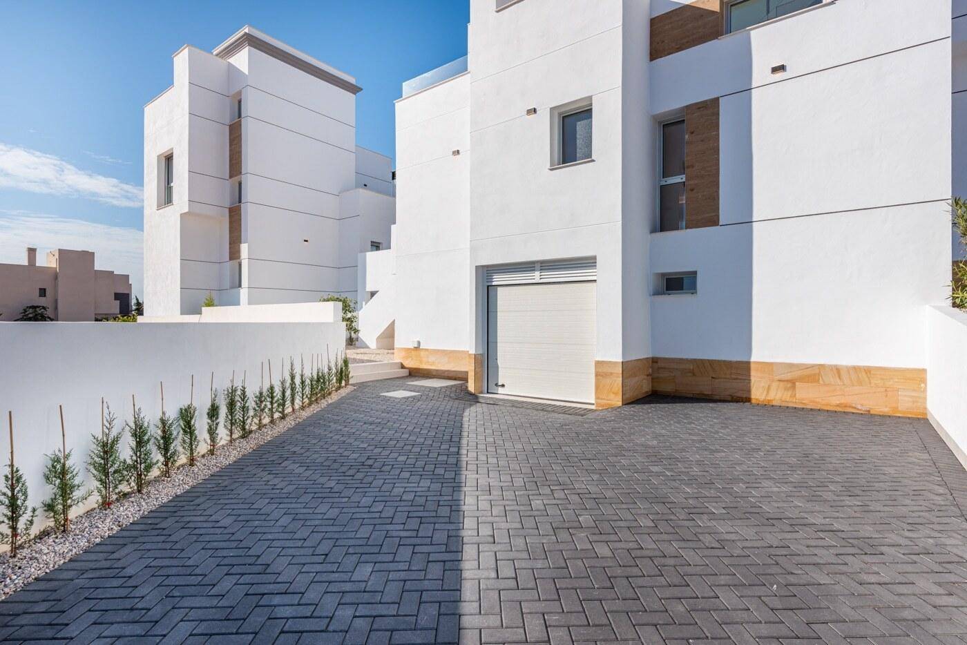 Moderne Auffahrt mit Pflastersteinen führt zur integrierten Garage des Hauses.