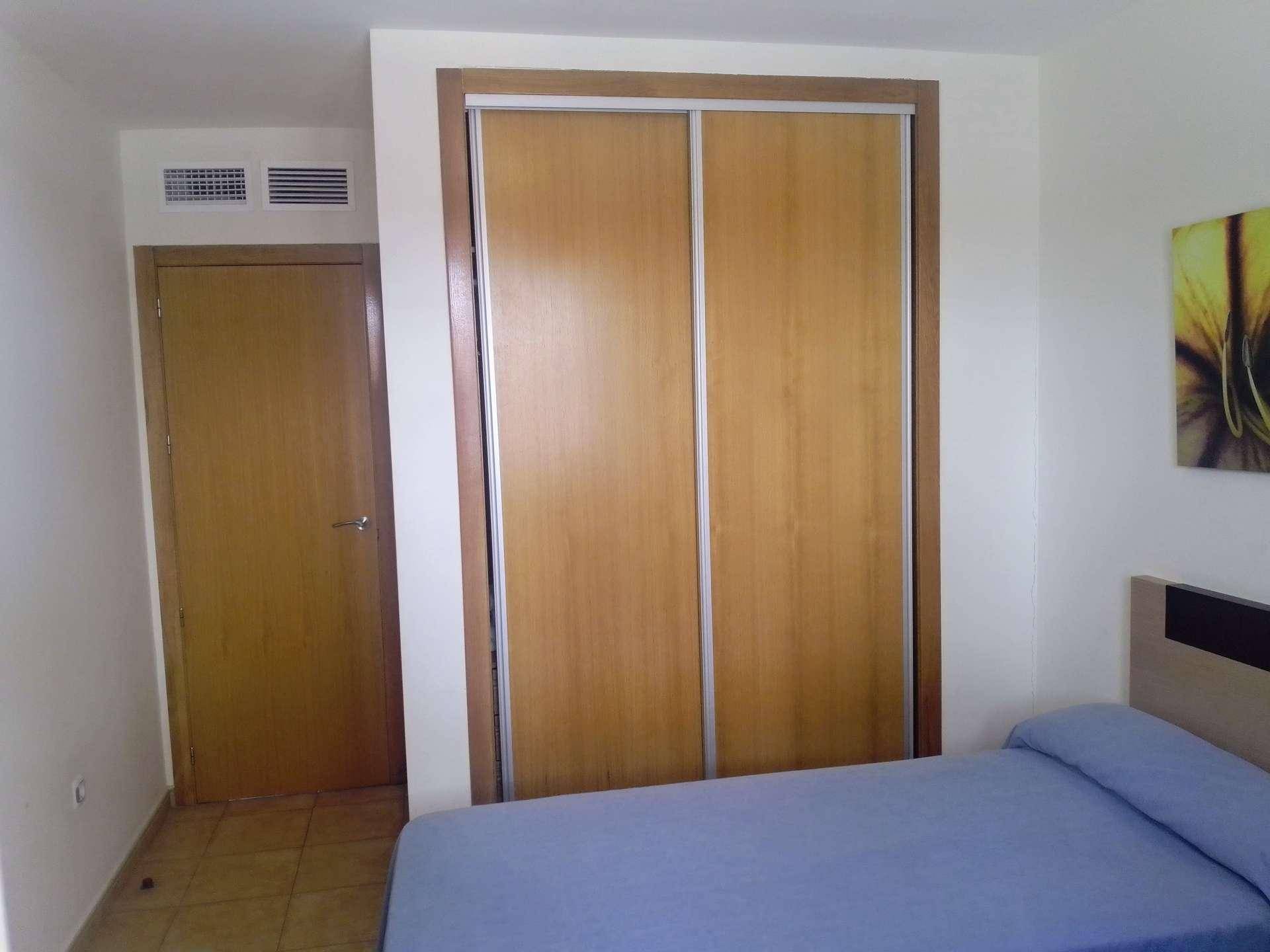 Schlafzimmer mit Einbauschrank und Fliesenboden, bietet ausreichend Platz für Kleidung.