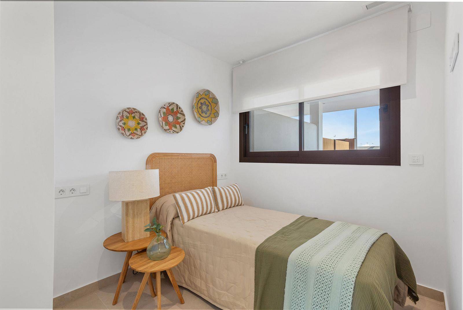 Schlafzimmer mit Einzelbett und Fenster, das viel Tageslicht hereinlässt.