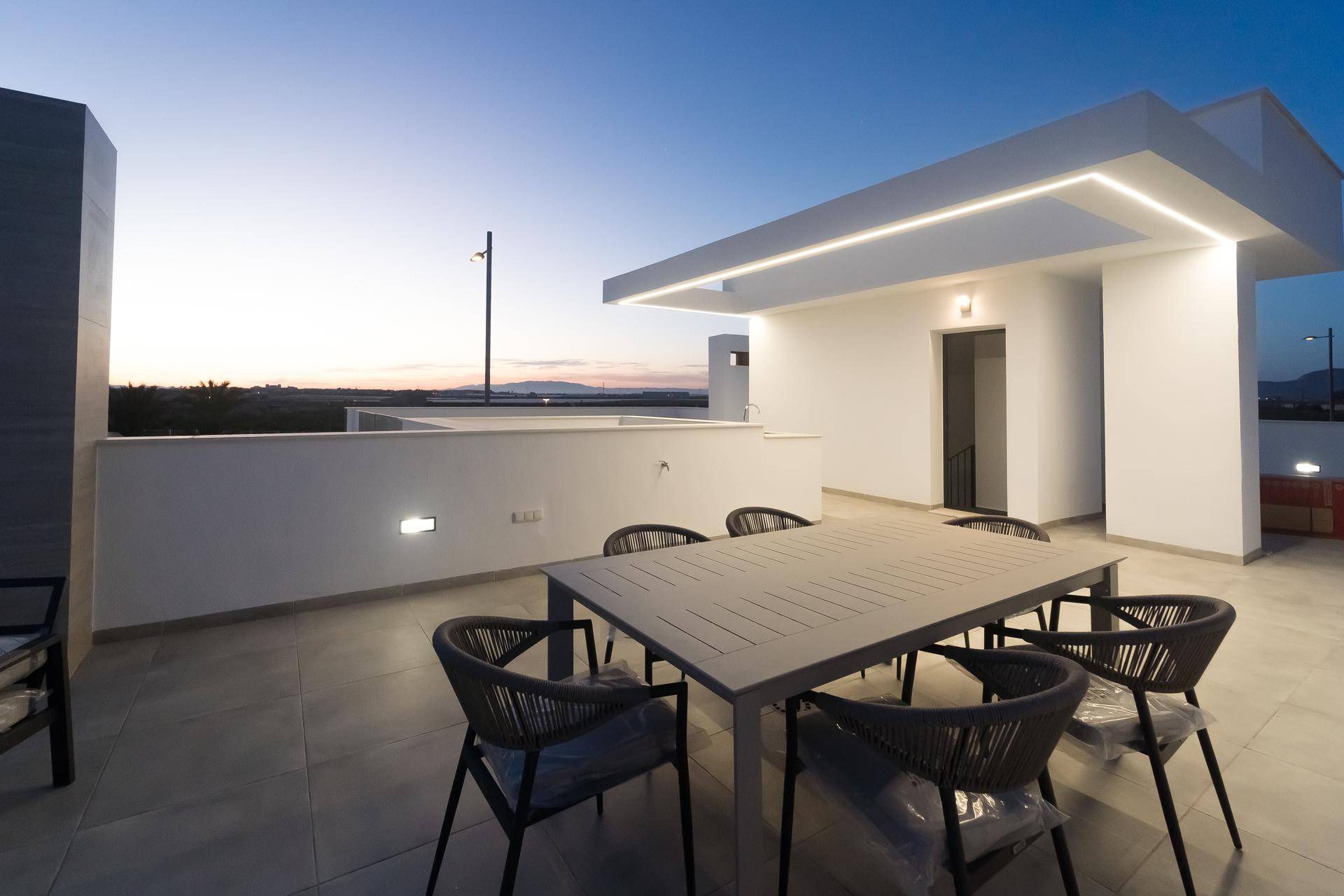 Gemütlicher Essbereich auf der Dachterrasse mit moderner Beleuchtung und weitem Blick.