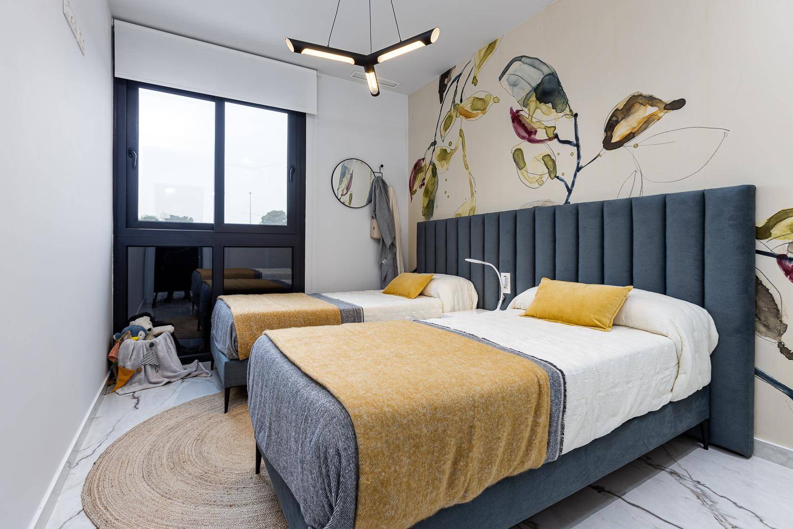 Lichtdurchflutetes Schlafzimmer mit zwei Einzelbetten, moderner Einrichtung und großem Fenster.