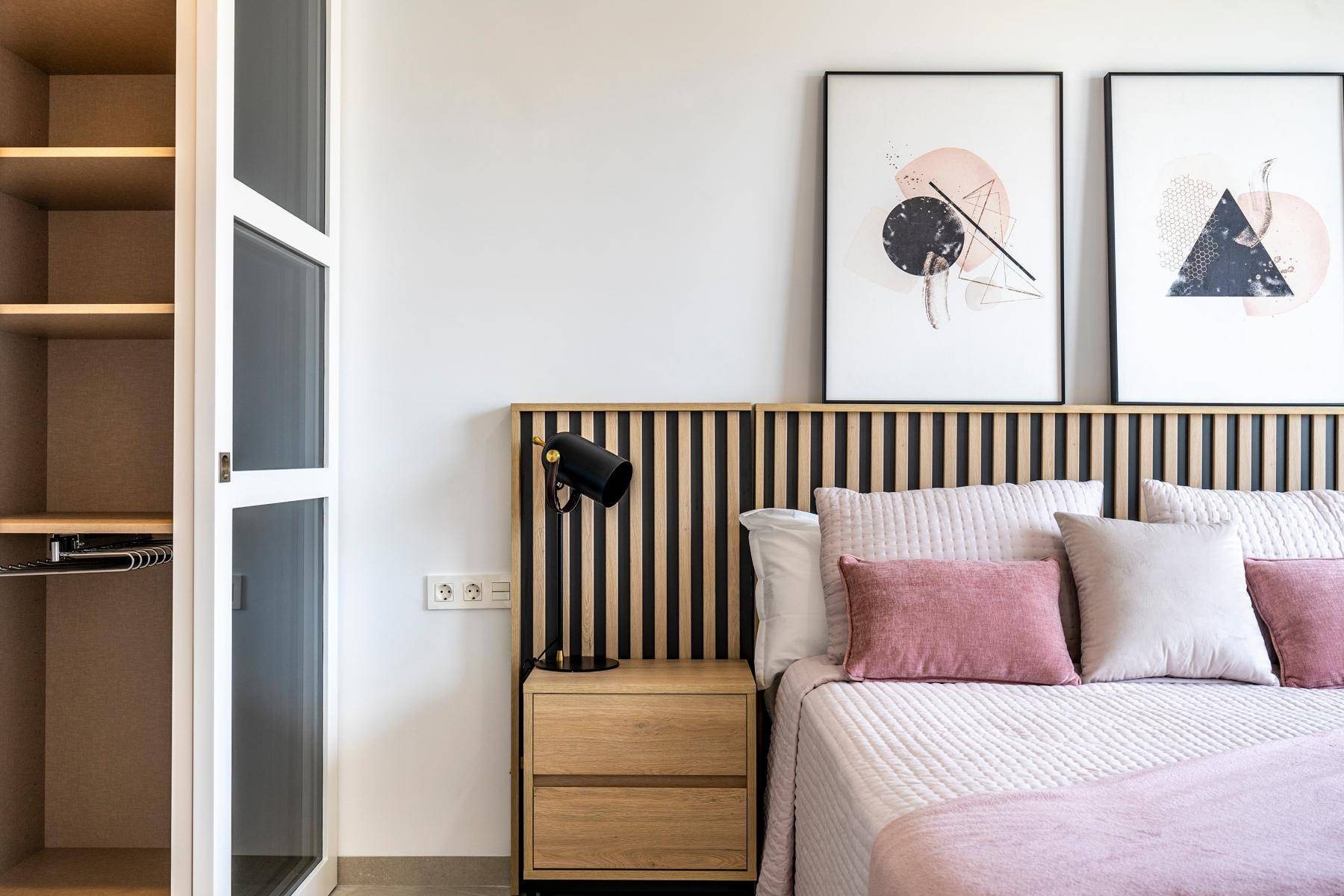 Modernes Schlafzimmer mit stilvollem Kopfteil, Nachttisch und abstrakter Kunst an der Wand.