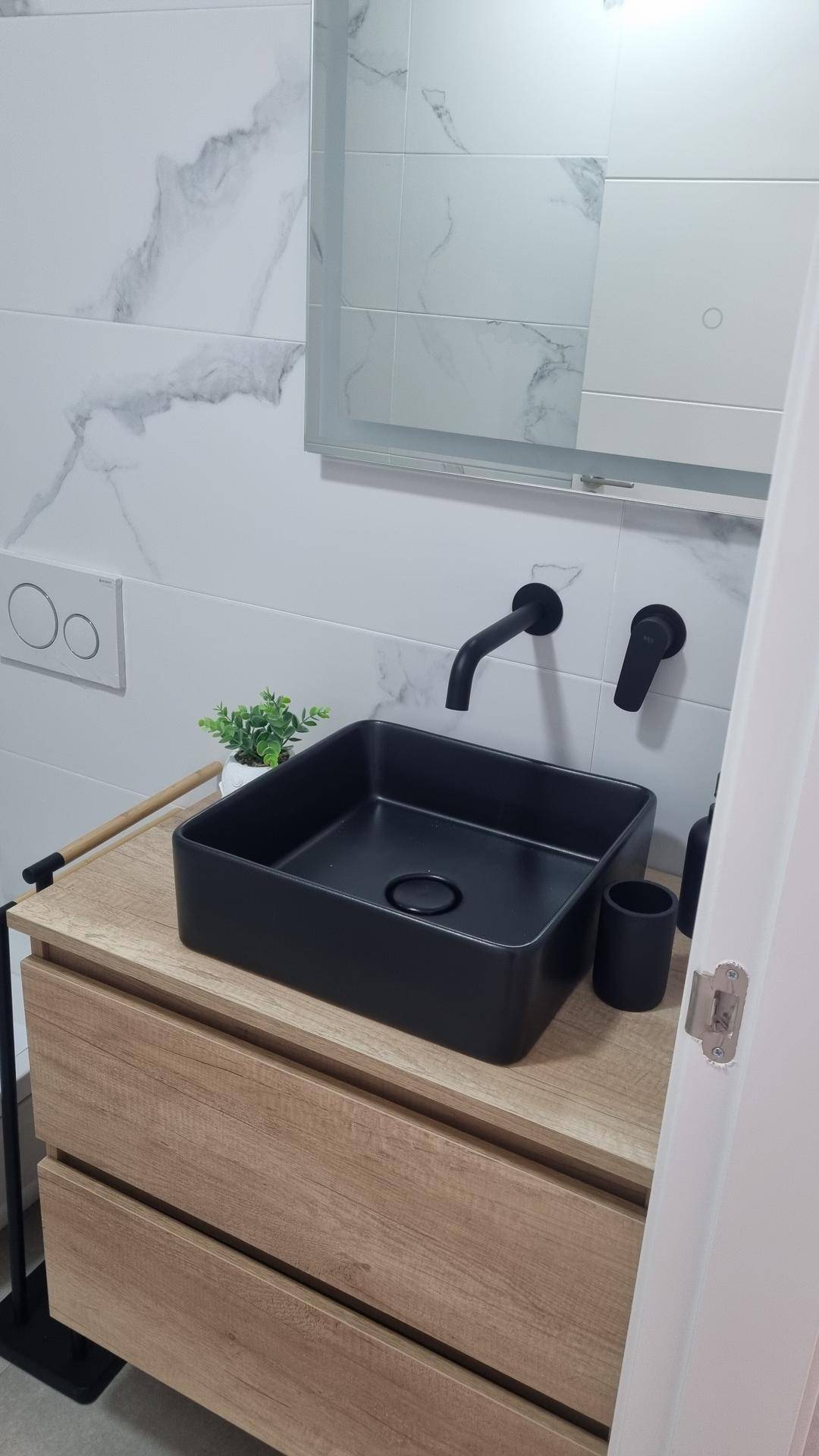 Modernes Badezimmer mit schwarzem Aufsatzwaschbecken und Holzunterschrank.