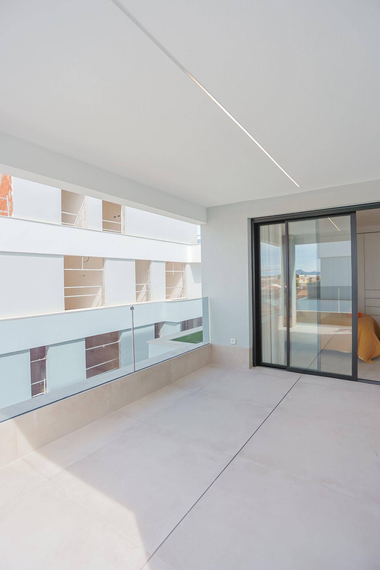 Heller Balkon mit Fliesenboden und Glasgeländer, ideal für entspannte Stunden im Freien.