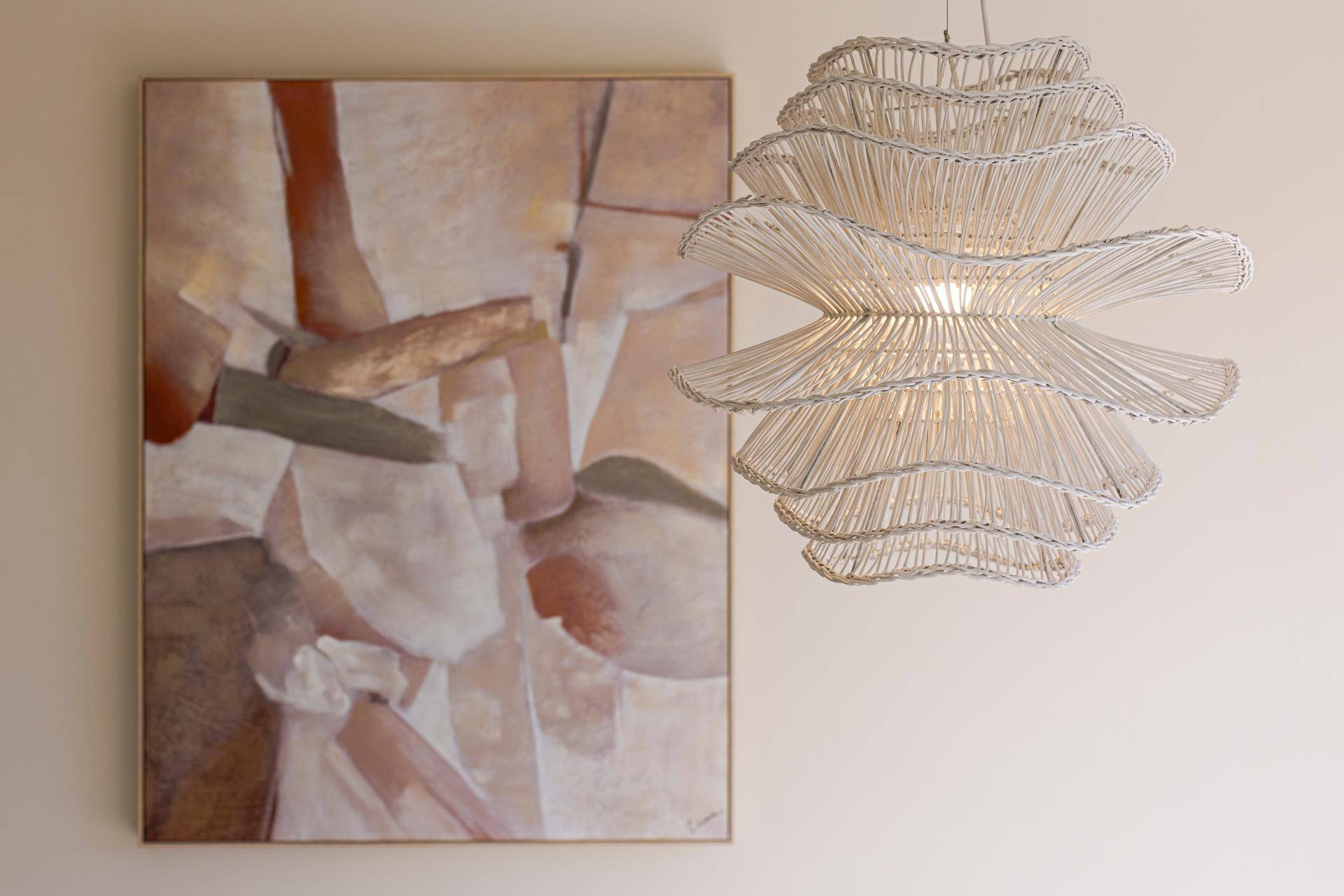 Detailaufnahme einer modernen Hängelampe und eines abstrakten Kunstwerks im Essbereich.
