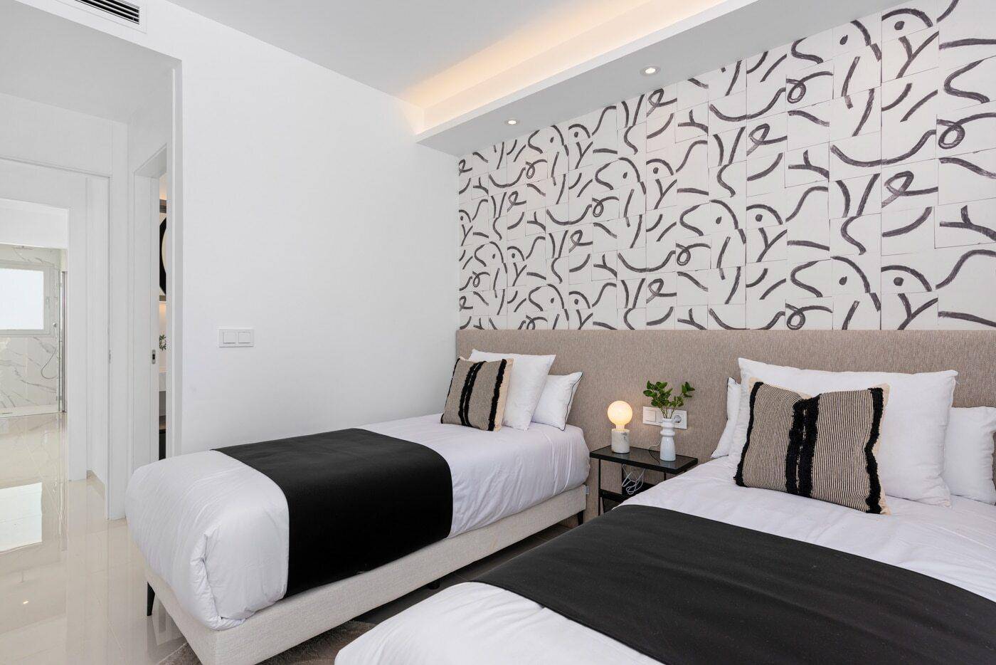 Helles Schlafzimmer mit zwei Einzelbetten und einer dekorativen Wandgestaltung.