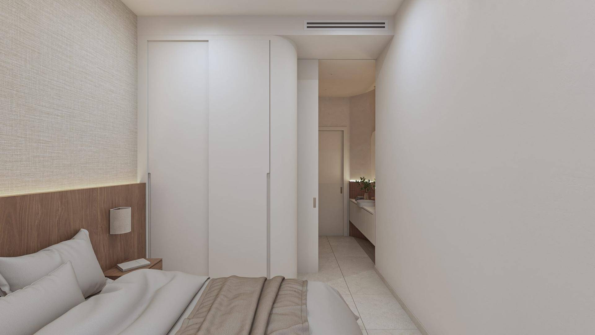 Schlafzimmer mit Einbauschränken und Blick auf das angrenzende moderne Badezimmer.