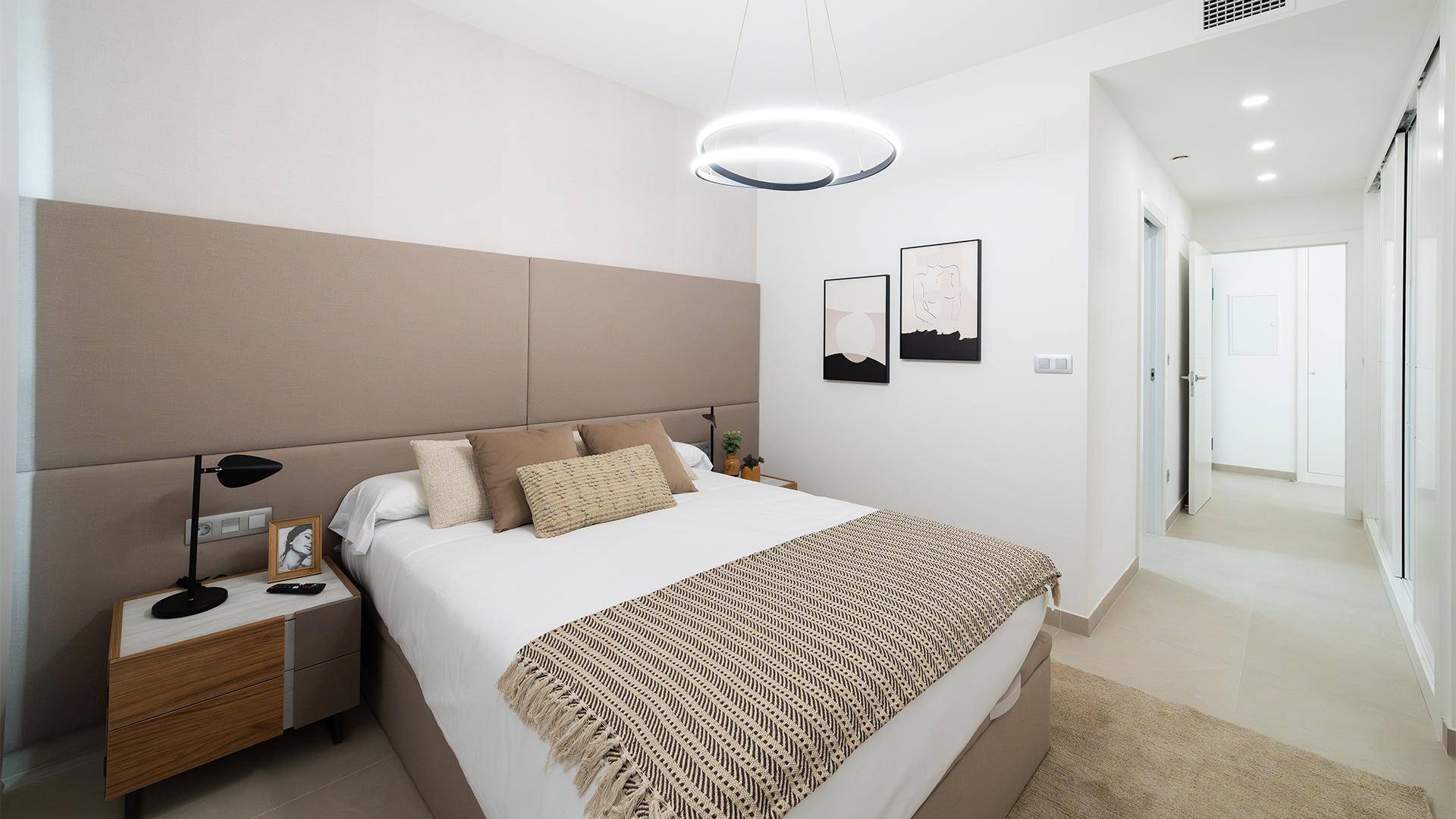 Modernes Schlafzimmer mit Doppelbett, beigem Kopfteil und hellem Marmorboden.