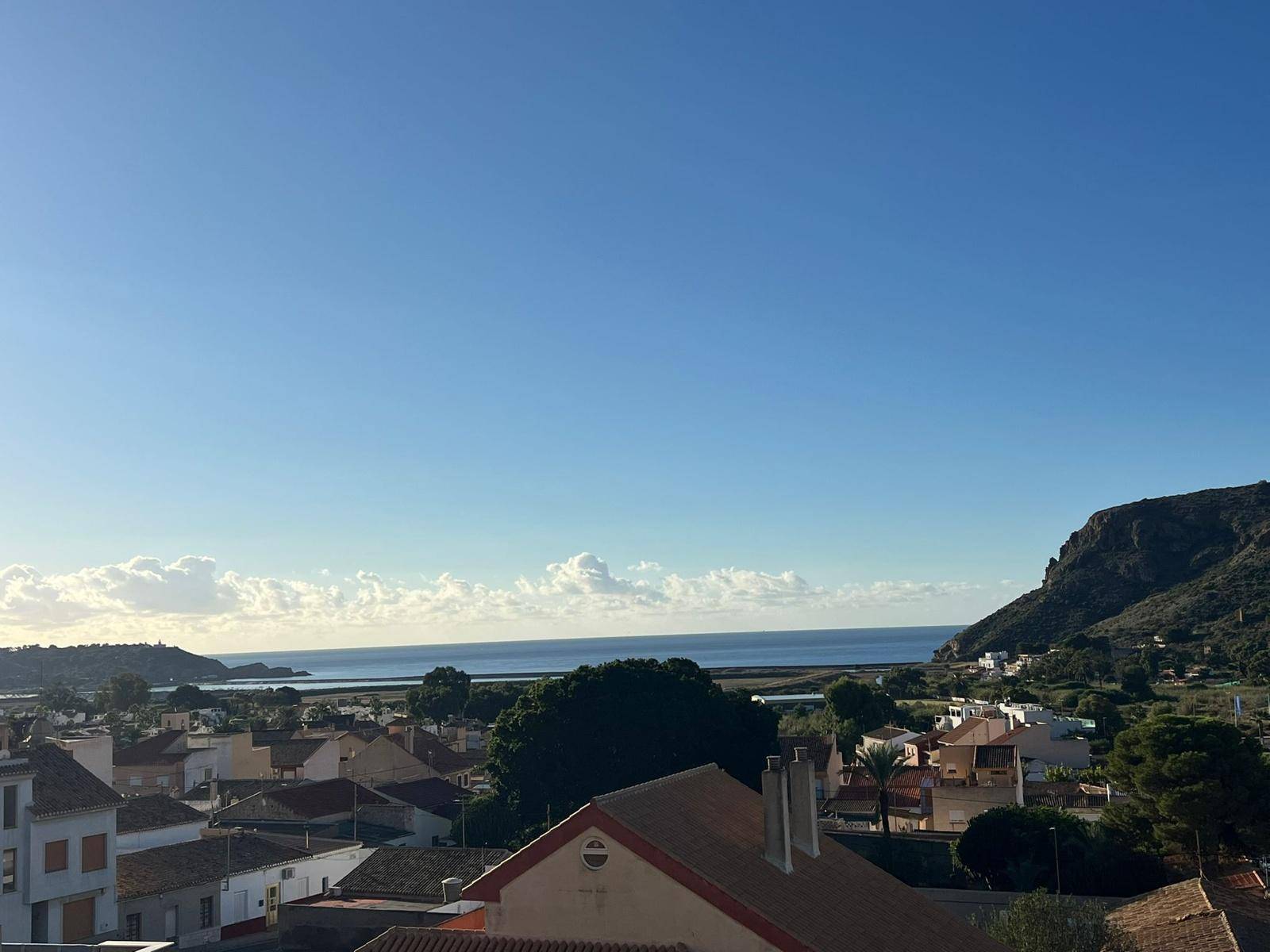 Panoramablick auf das weite Meer, die Küstenlinie und die umliegende bergige Landschaft.