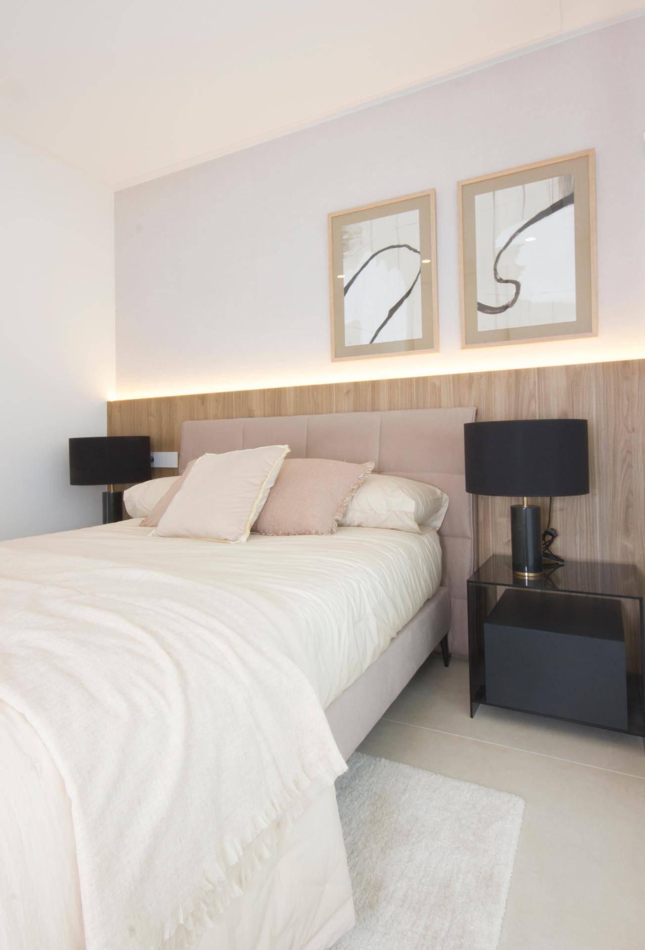 Modernes Schlafzimmer mit beigem Bett, Nachttischen und indirekter Beleuchtung.