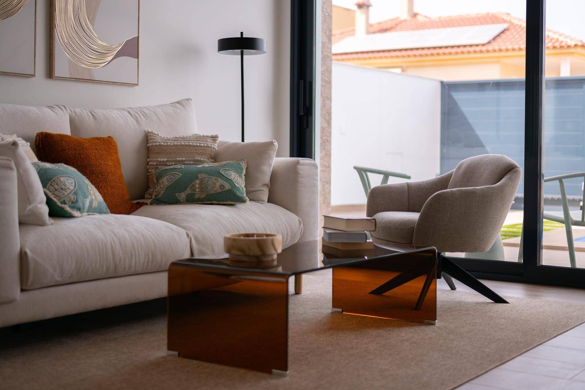 Gemütlicher Wohnbereich mit hellem Sofa, modernen Kissen und Zugang zur Außenterrasse.