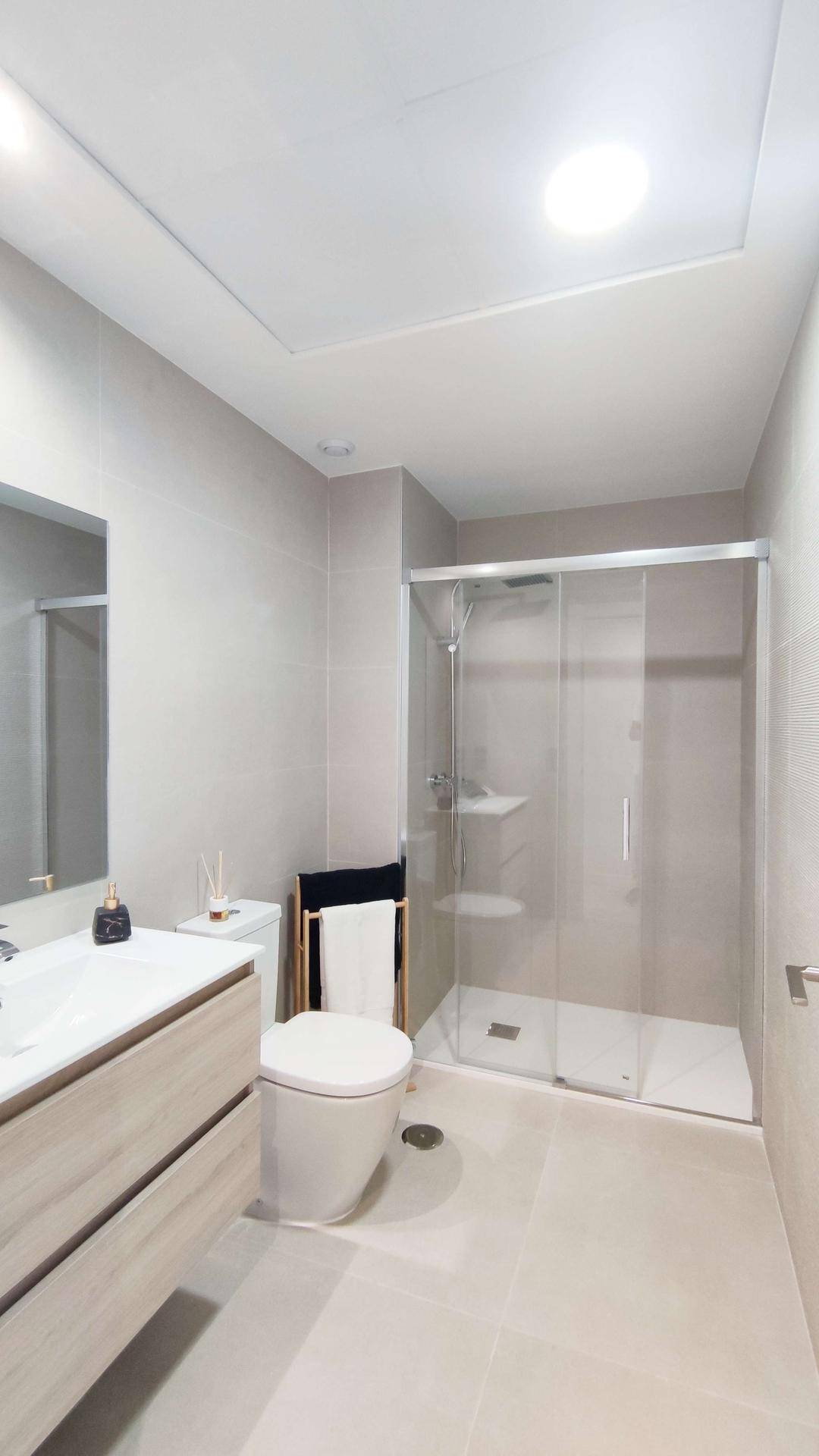 Helles Badezimmer mit Duschkabine, modernem Waschtisch und WC.