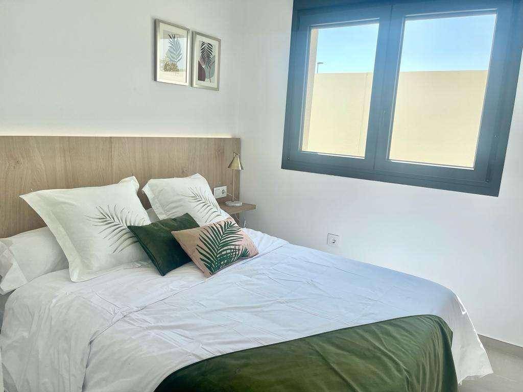 Helles Schlafzimmer mit Doppelbett, Holz-Kopfteil und großem Fenster für viel Tageslicht.
