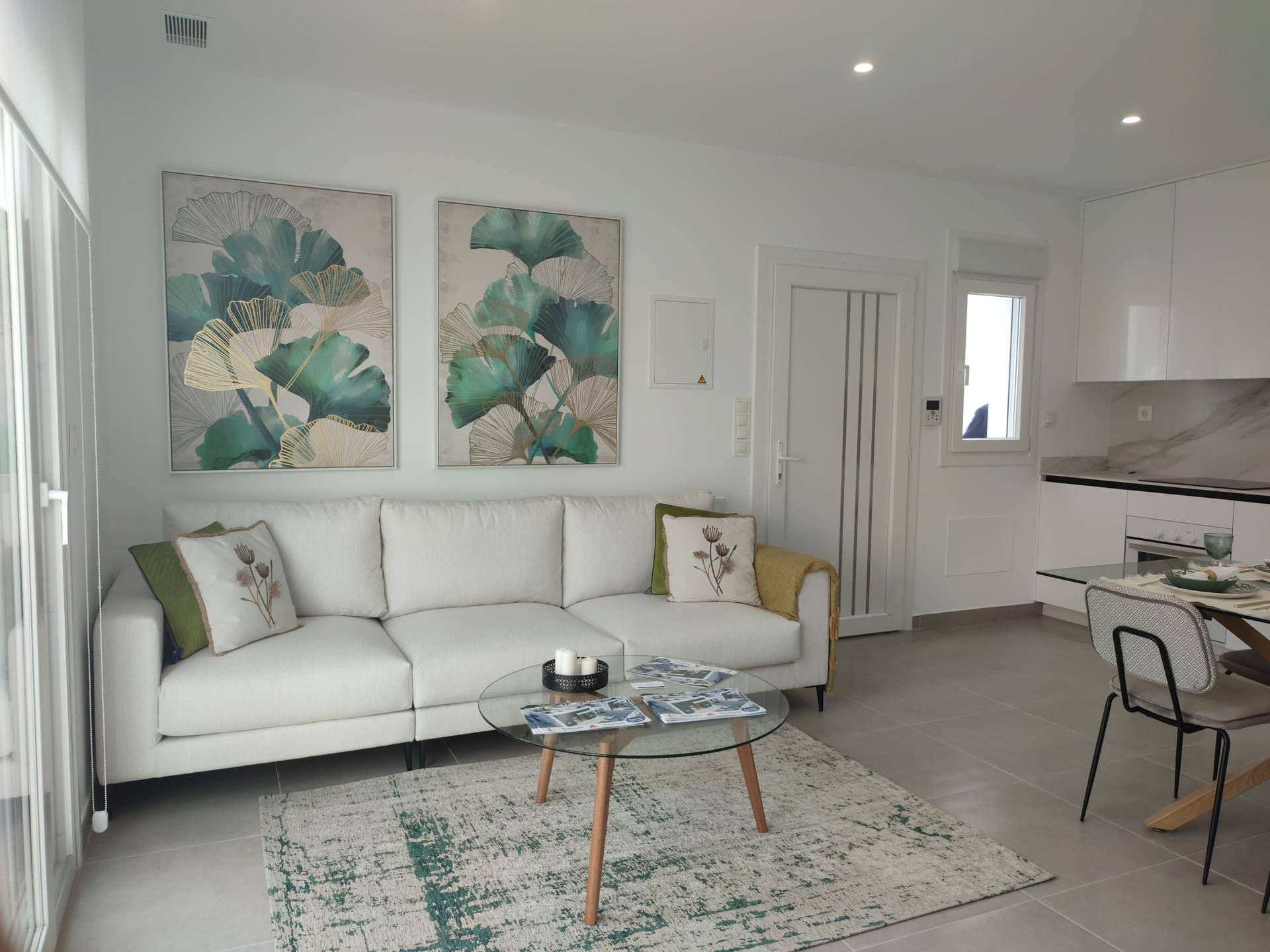 Gemütlicher Wohnbereich mit weißem Sofa, Couchtisch und offenem Übergang zur modernen Küche.