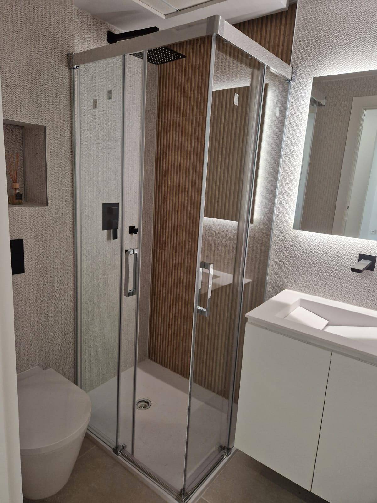 Modernes Badezimmer mit Duschkabine, Toilette und Waschbecken, ausgestattet mit Regendusche.