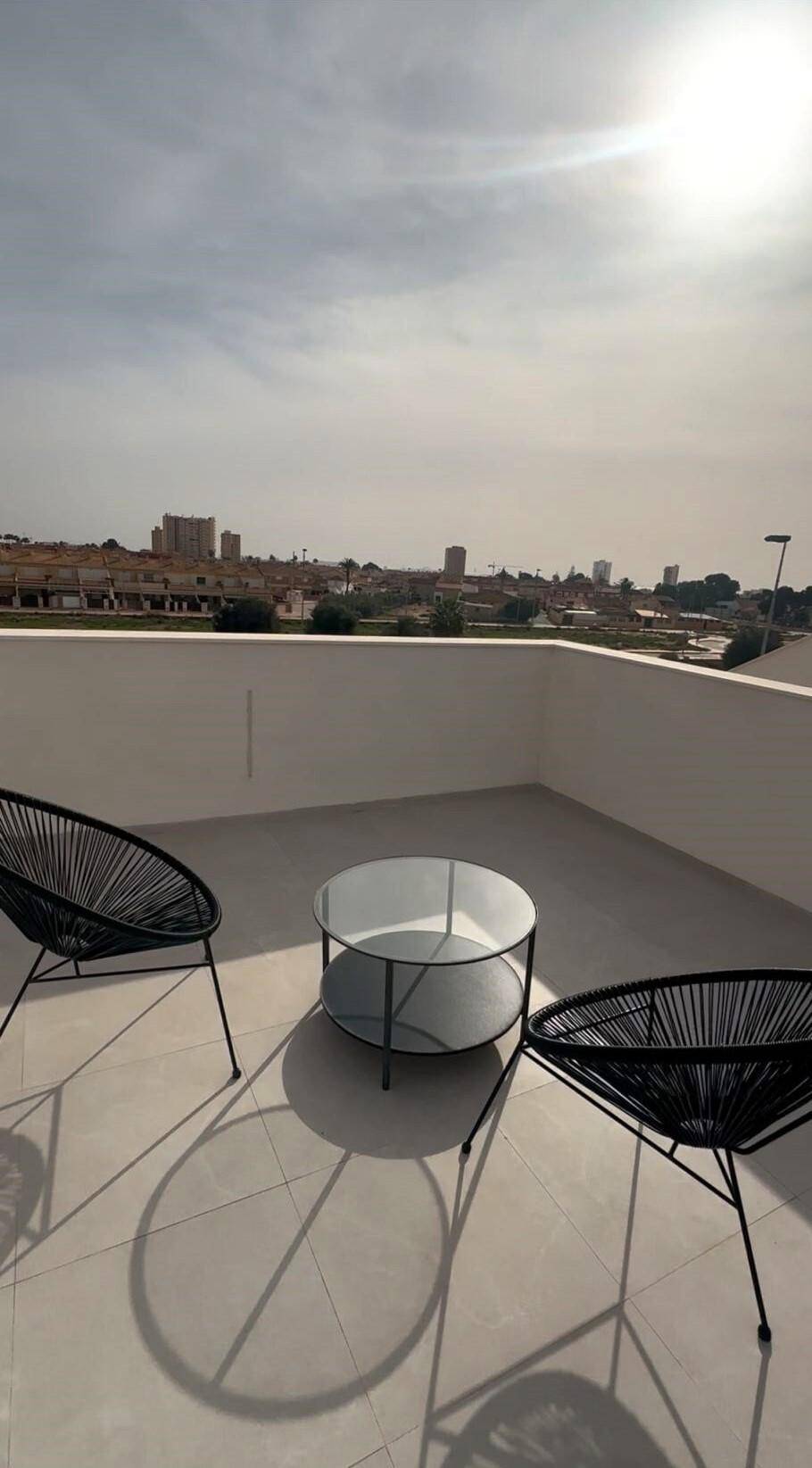 Sonnige Dachterrasse mit modernen Stühlen und einem Glastisch, ideal zum Entspannen.