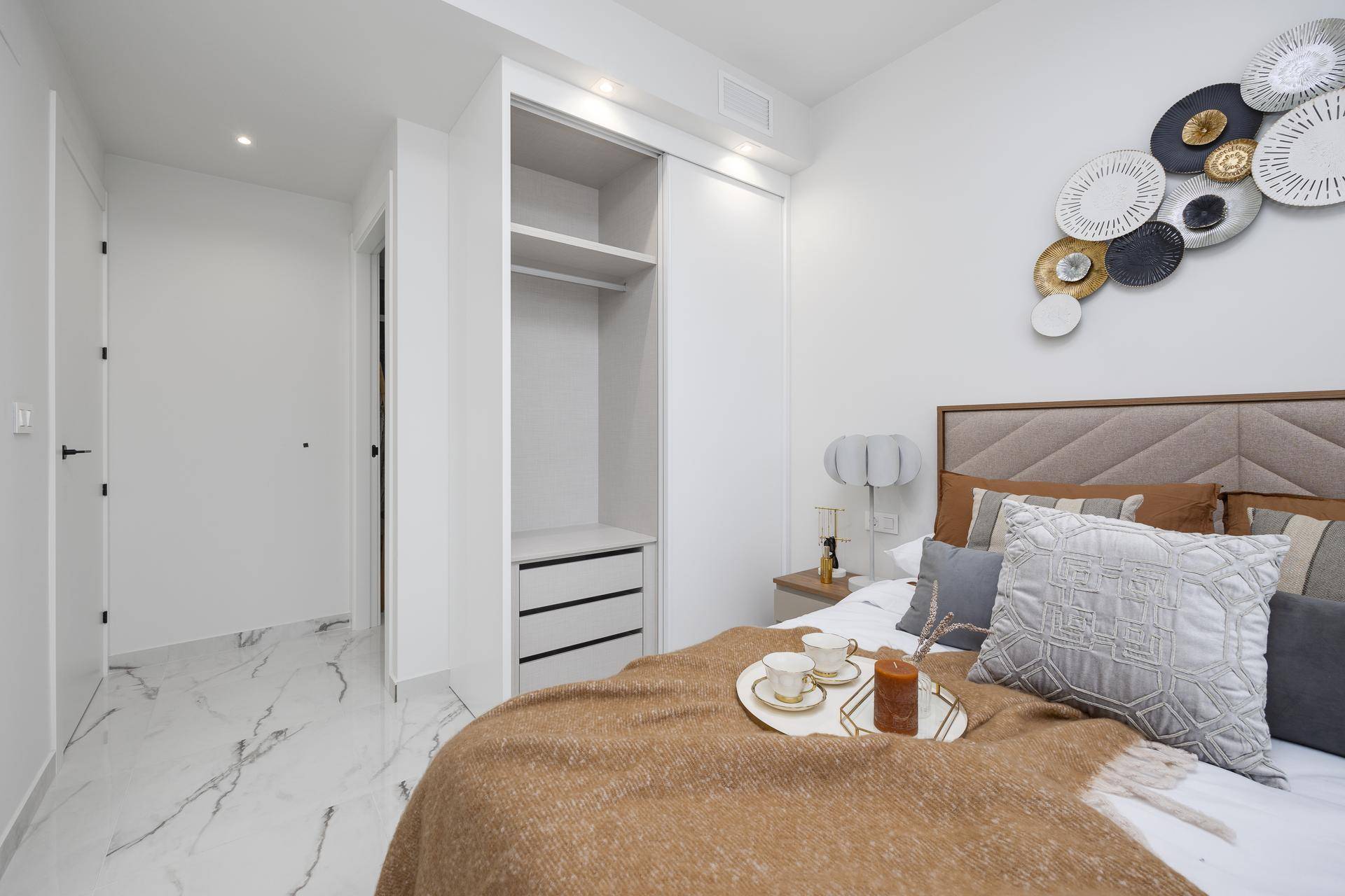 Schlafzimmer mit integriertem Kleiderschrank, Marmorboden und dekorativer Wandkunst.
