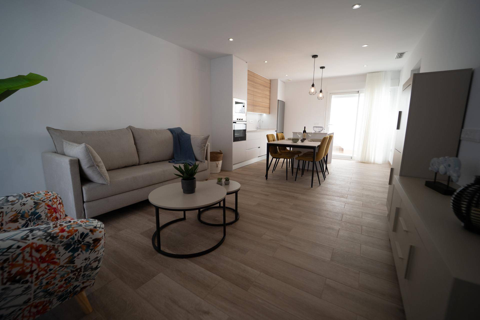 Helles, offenes Wohn- und Esszimmer mit moderner Einrichtung, Holzboden und Zugang zur Terrasse.