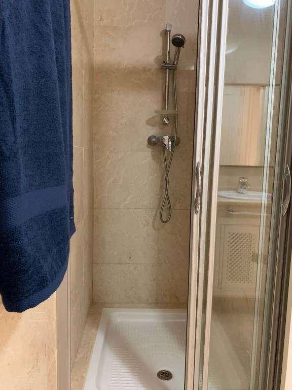 Duschbereich im Badezimmer mit Glasabtrennung und beigefarbenen Fliesen.