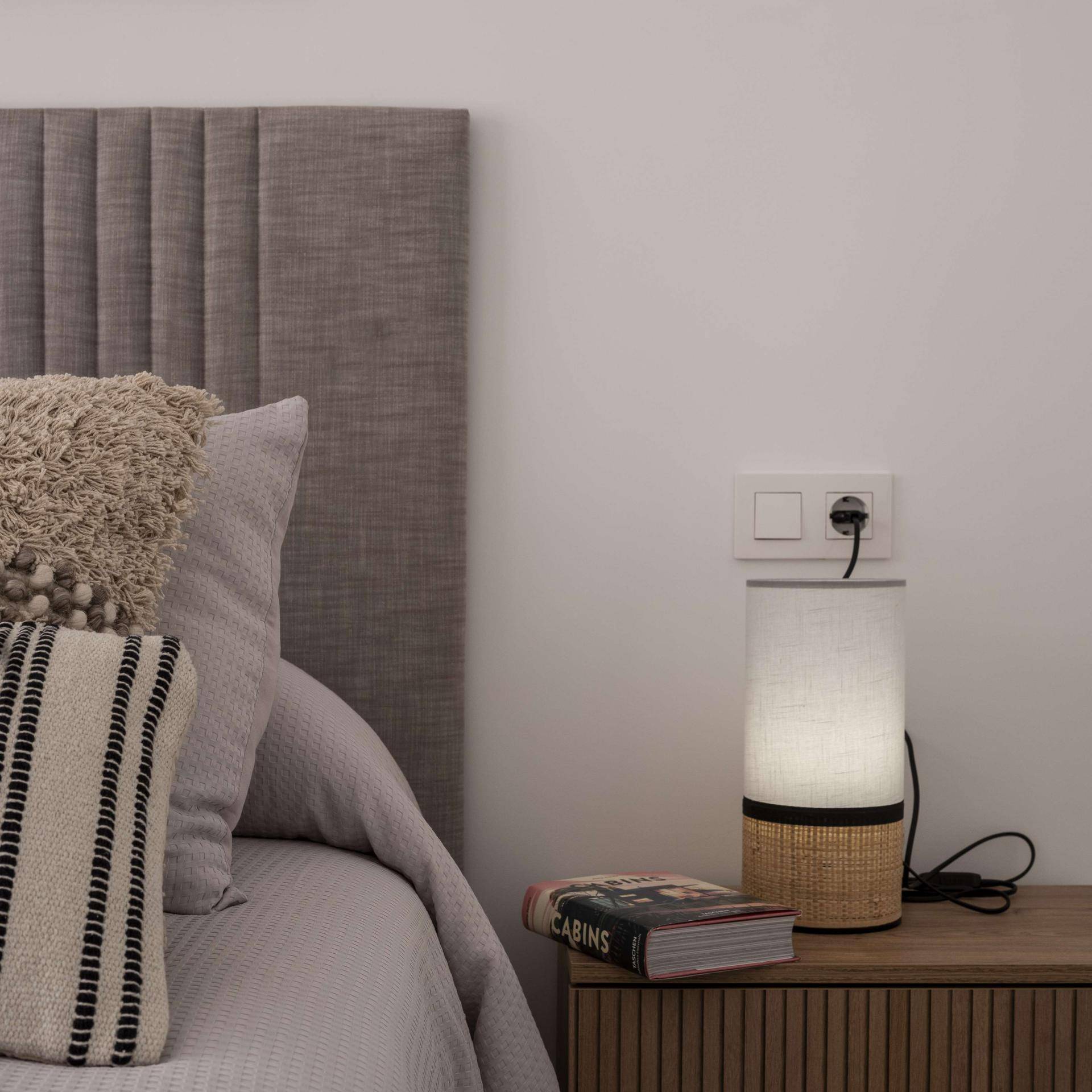 Detailansicht des Nachttisches mit Lampe und Buch im gemütlichen Schlafzimmer.