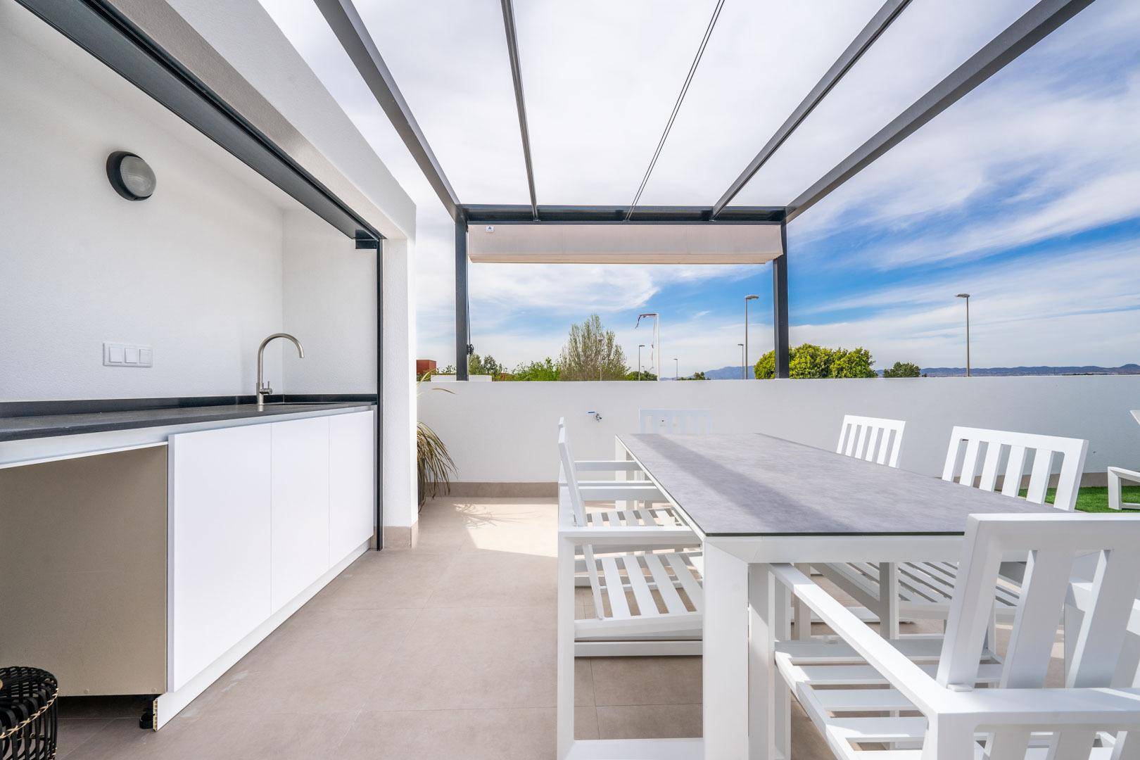 Geräumige Dachterrasse mit moderner Außenküche und Essbereich unter einer Pergola.