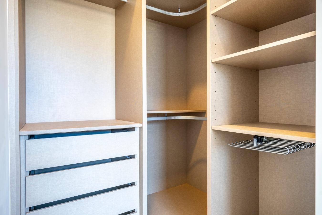 Geräumiger begehbarer Kleiderschrank mit offenen Regalen, Schubladen und Kleiderstangen für optimale Organisation.