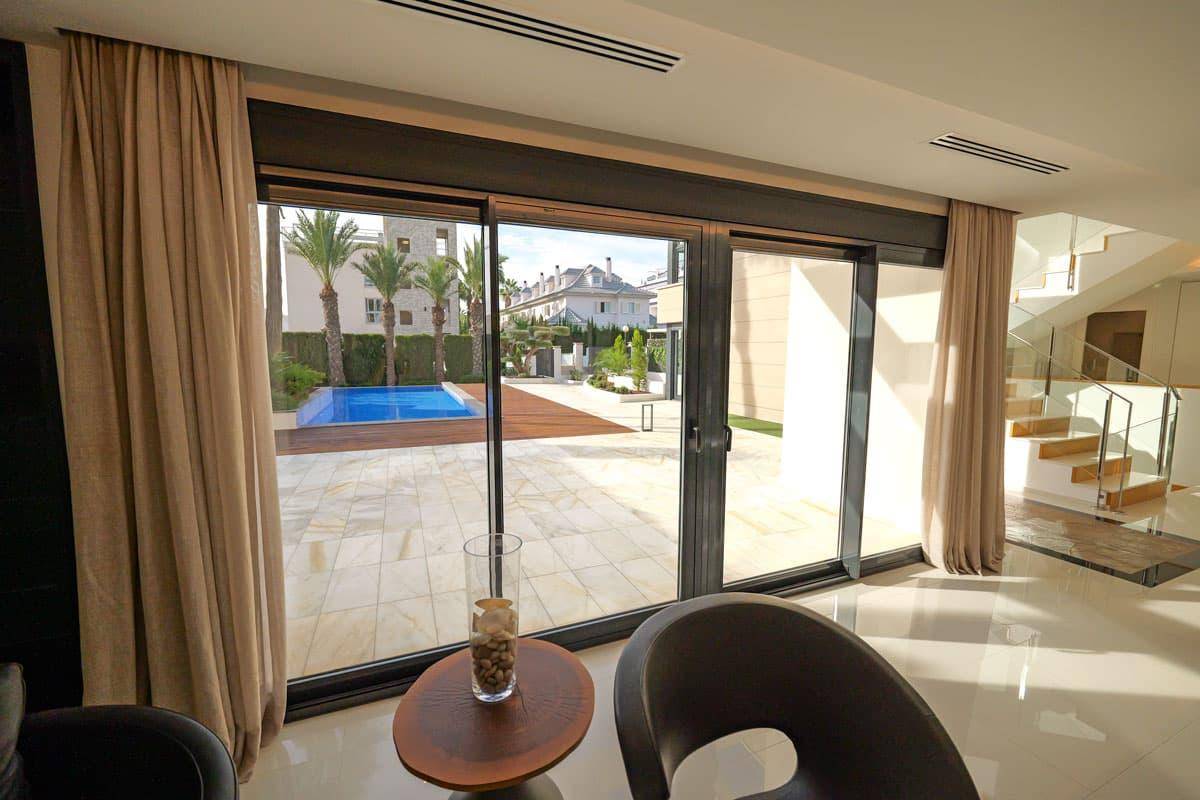 Helles Wohnzimmer mit großen Schiebetüren, die den Blick auf den Pool und den Garten freigeben.