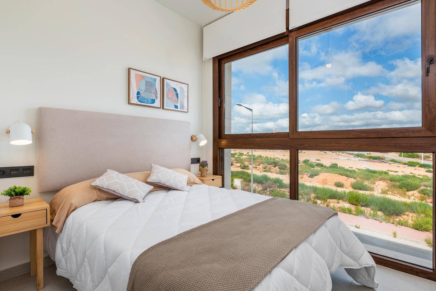 Schlafzimmer mit Doppelbett und großen Fenstern, die einen weiten Blick auf die Landschaft bieten.